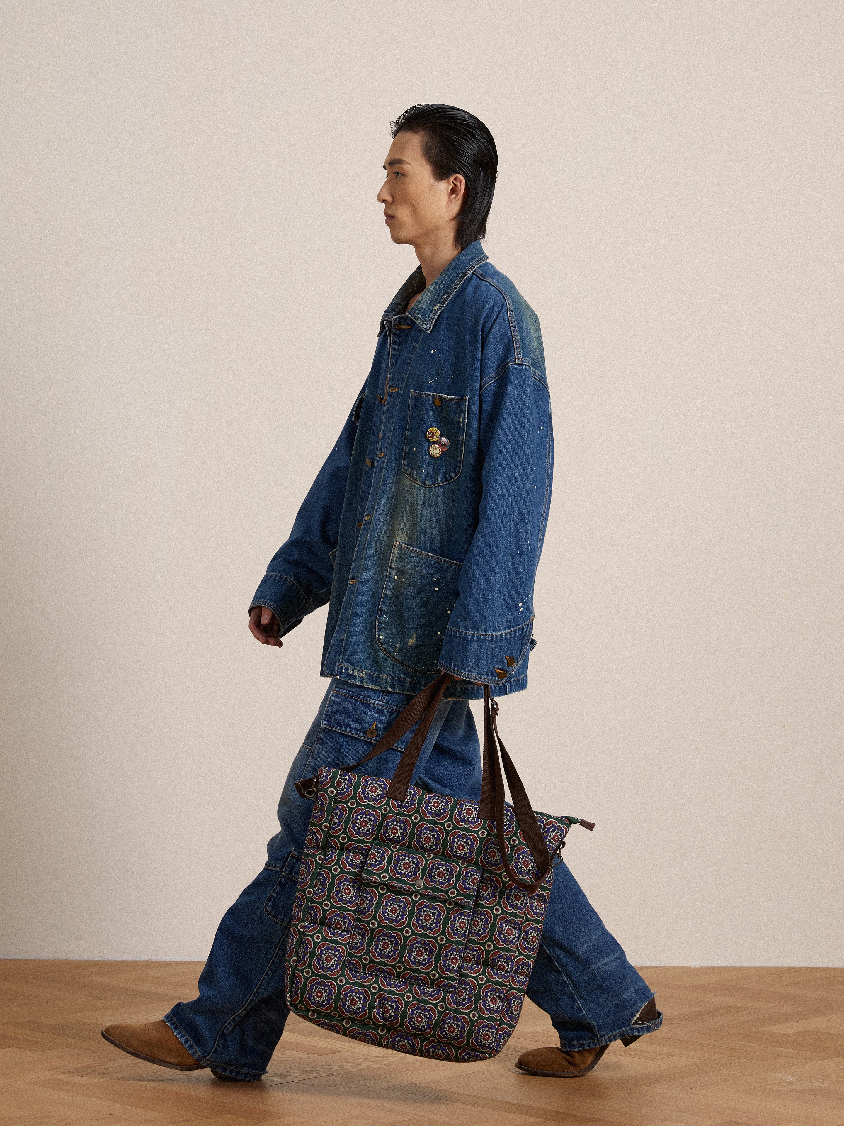 A Kavir Denim Painter Jacket-clad artist walking with a Found tote bag.