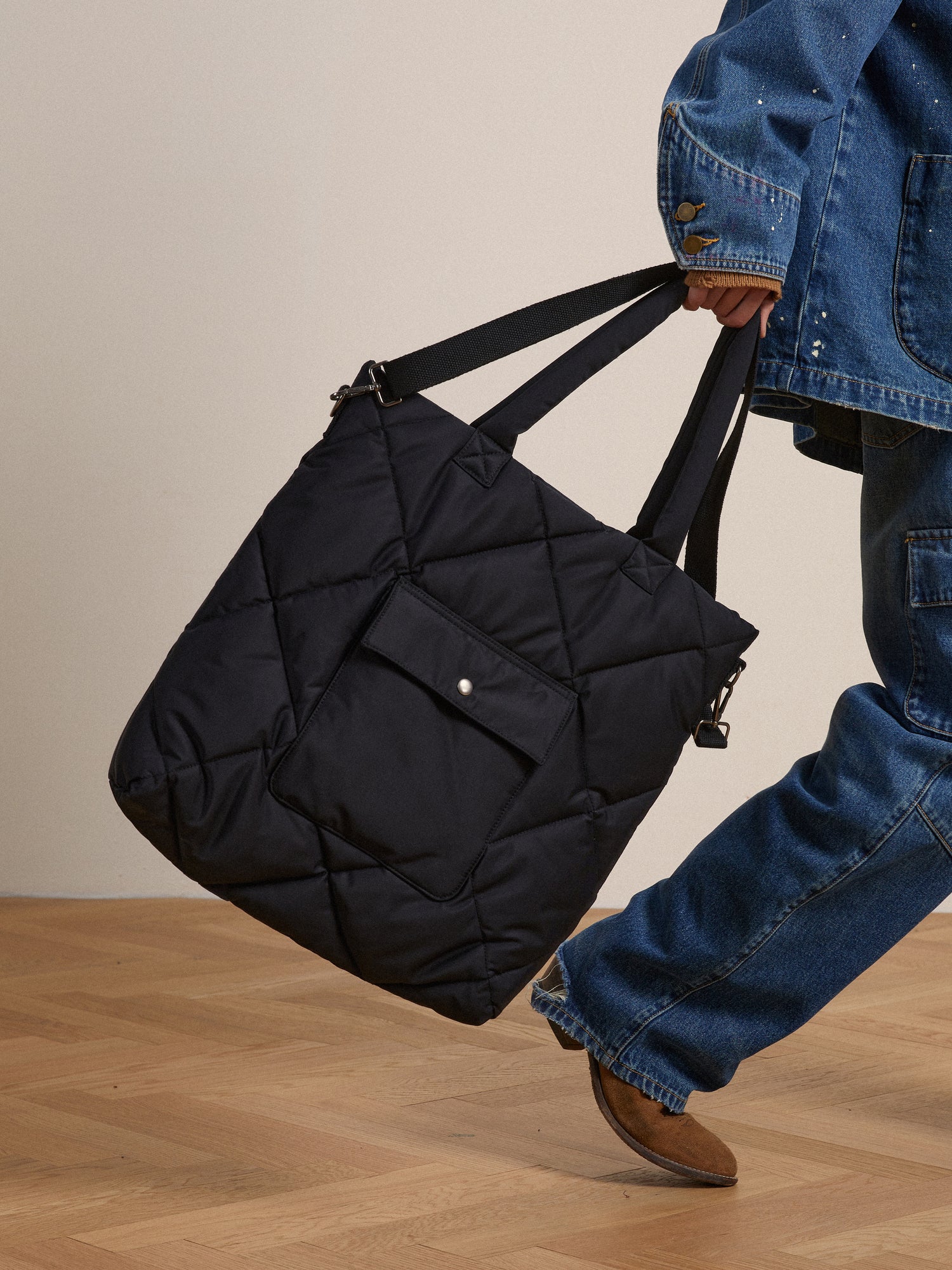 A man carrying a Profound Dayer Nylon Quilted Bag in black.