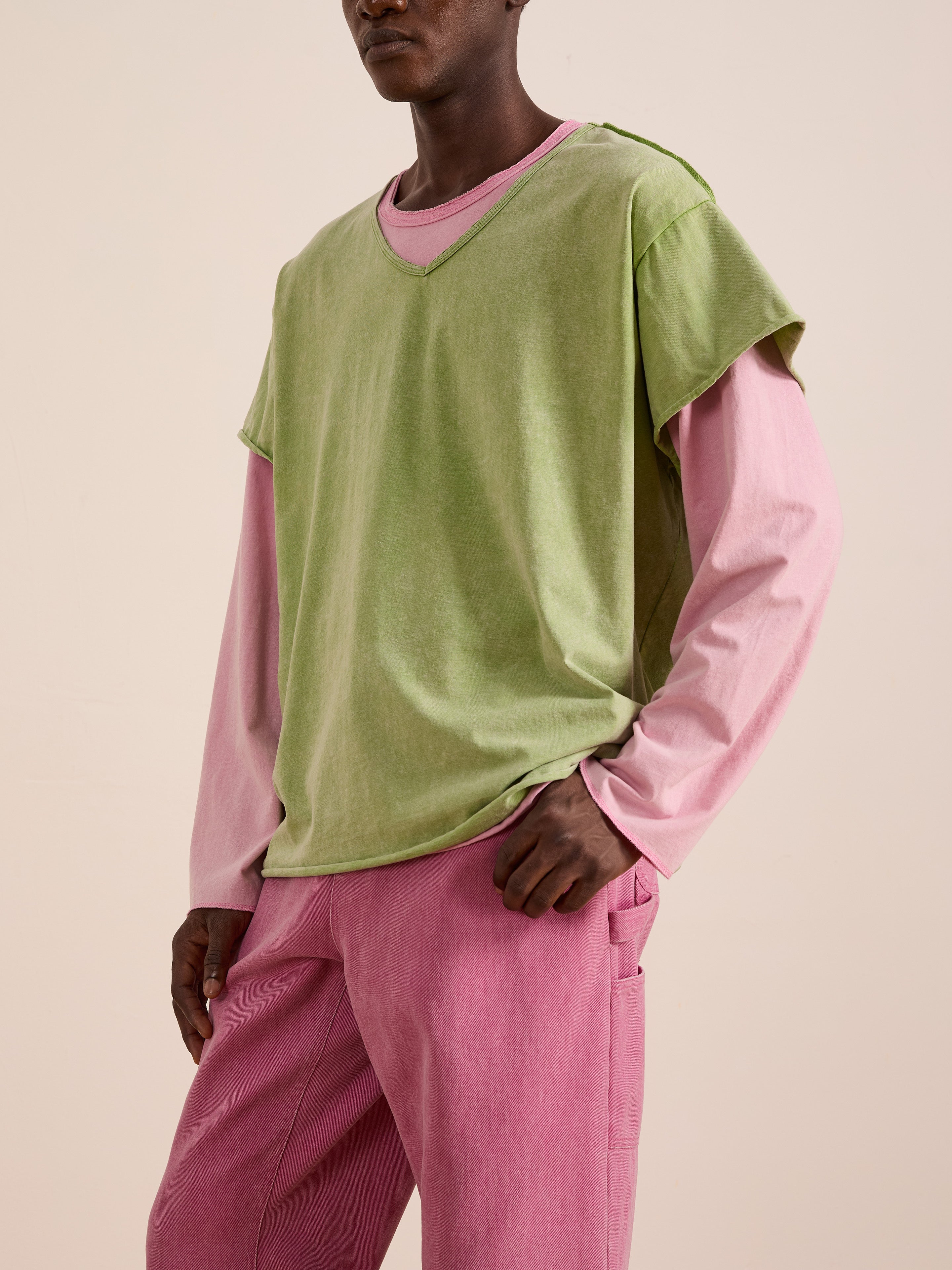 A person wears a green FOUND Double Layer LS Tee over a pink long-sleeve shirt and pink pants, standing against a neutral background.