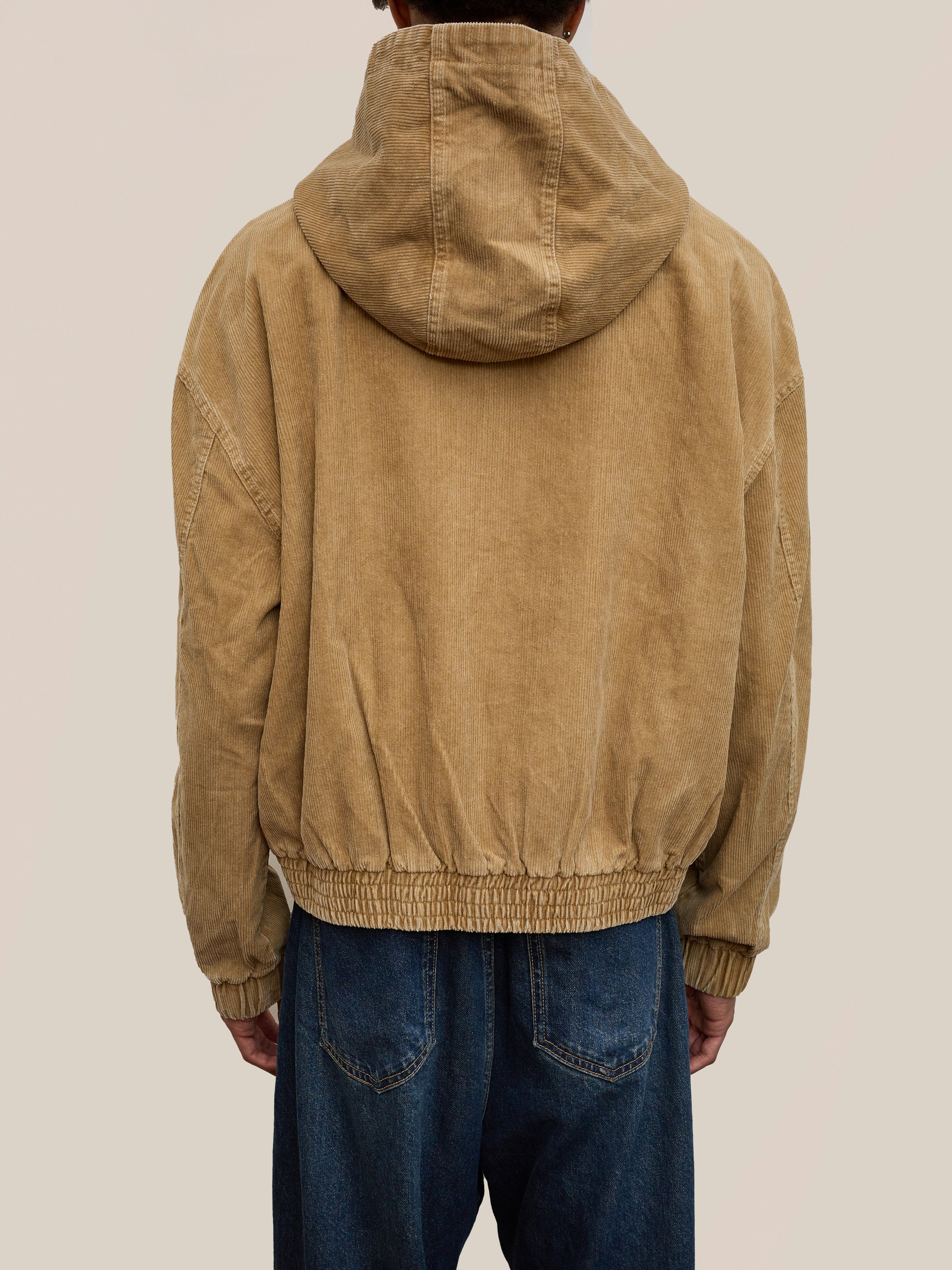 A person wearing the FOUND Corduroy Zip Up Hoodie in tan with blue jeans, shown from the back against a plain light background.