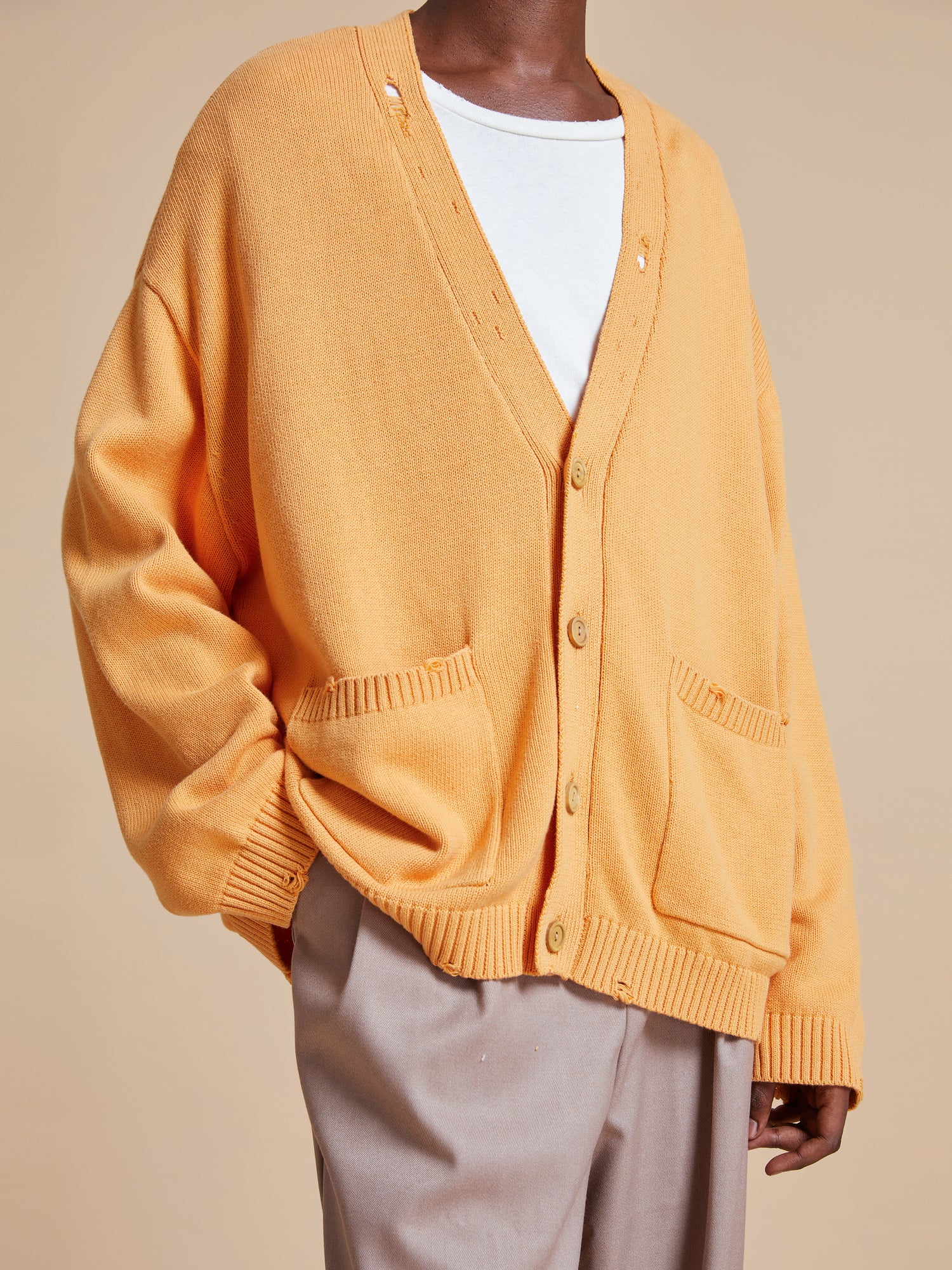 The model is wearing a yellow Found Cadmium Distressed Cardigan sweater.
