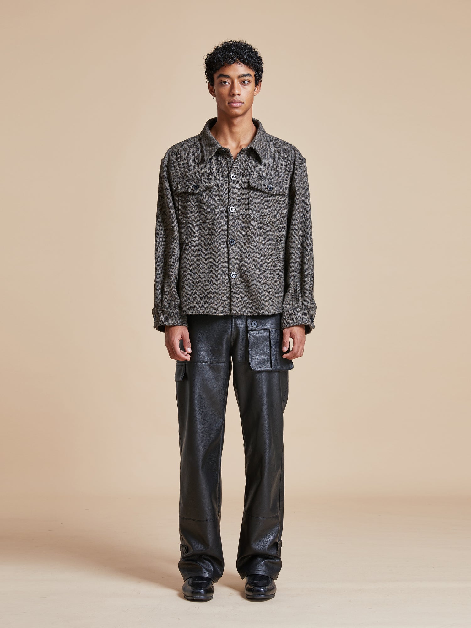 The model is wearing a Raven Herringbone Overshirt by Found and leather pants.