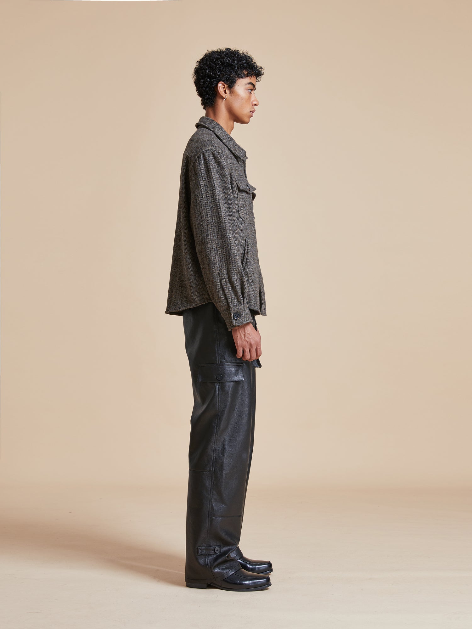 A man wearing black leather pants and a Raven Herringbone Overshirt by Found.
