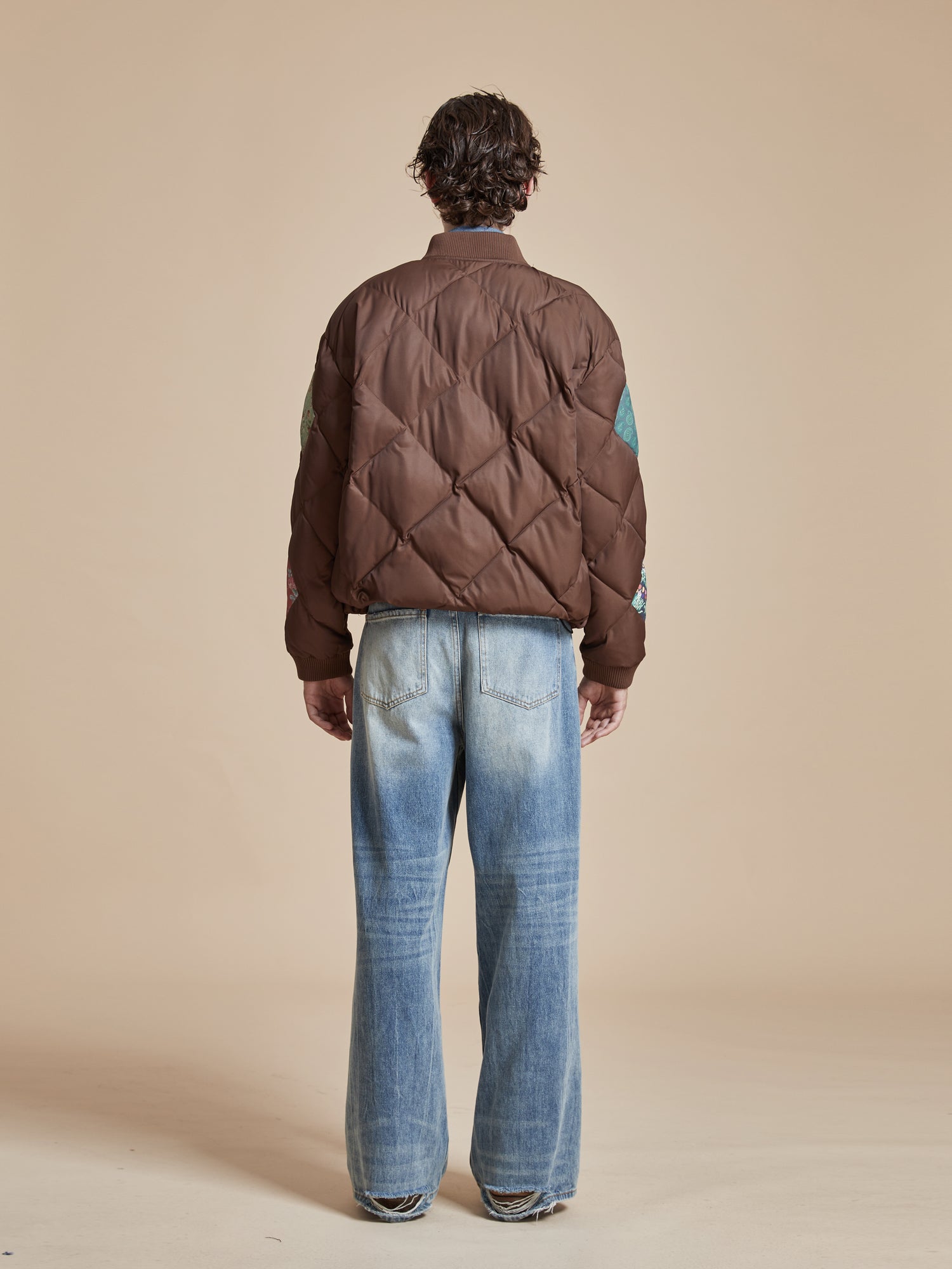 A man wearing jeans and a Found Diamond Quilt Patchwork Jacket.