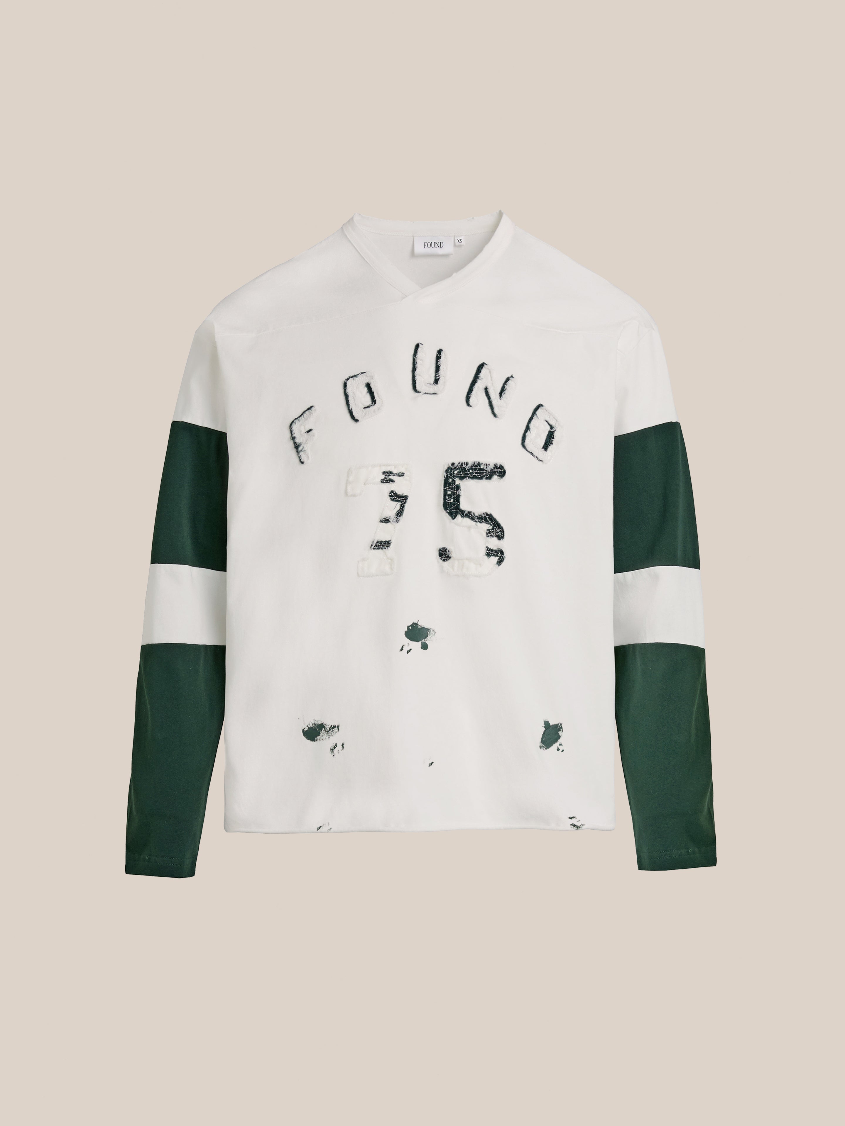 Relax in style with the FOUND Distressed LS Team Jersey. This relaxed-fit, vintage sportswear piece features dark green sleeves, white bands, and distressed "FOUND 75" text on the front—a must-have for laid-back fashion lovers.