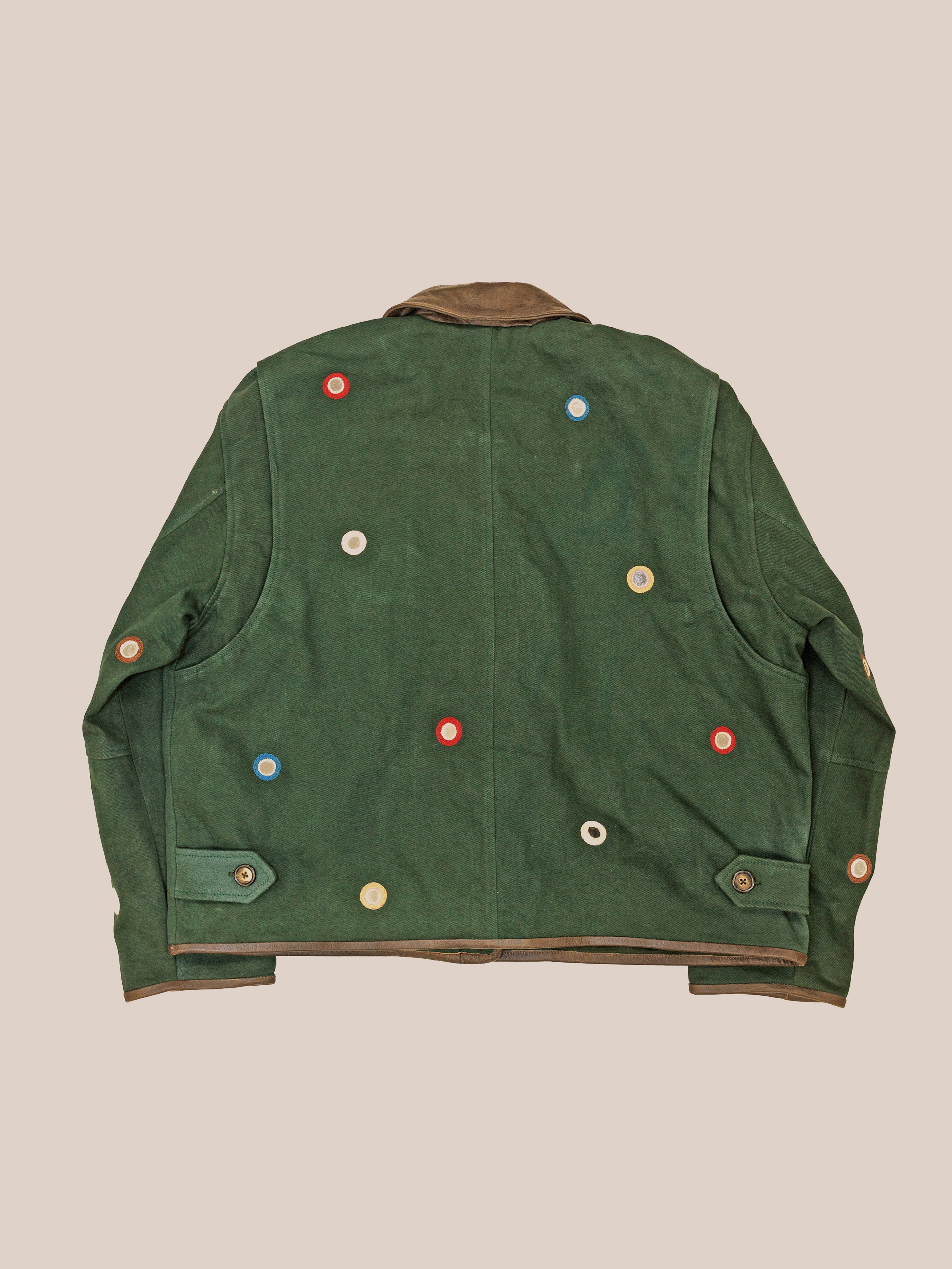 The Hand Embroidered Mirror Abhala Jacket by Found is a green cotton twill piece featuring multicolored circular buttons on the back and sleeves, shown on a neutral background.