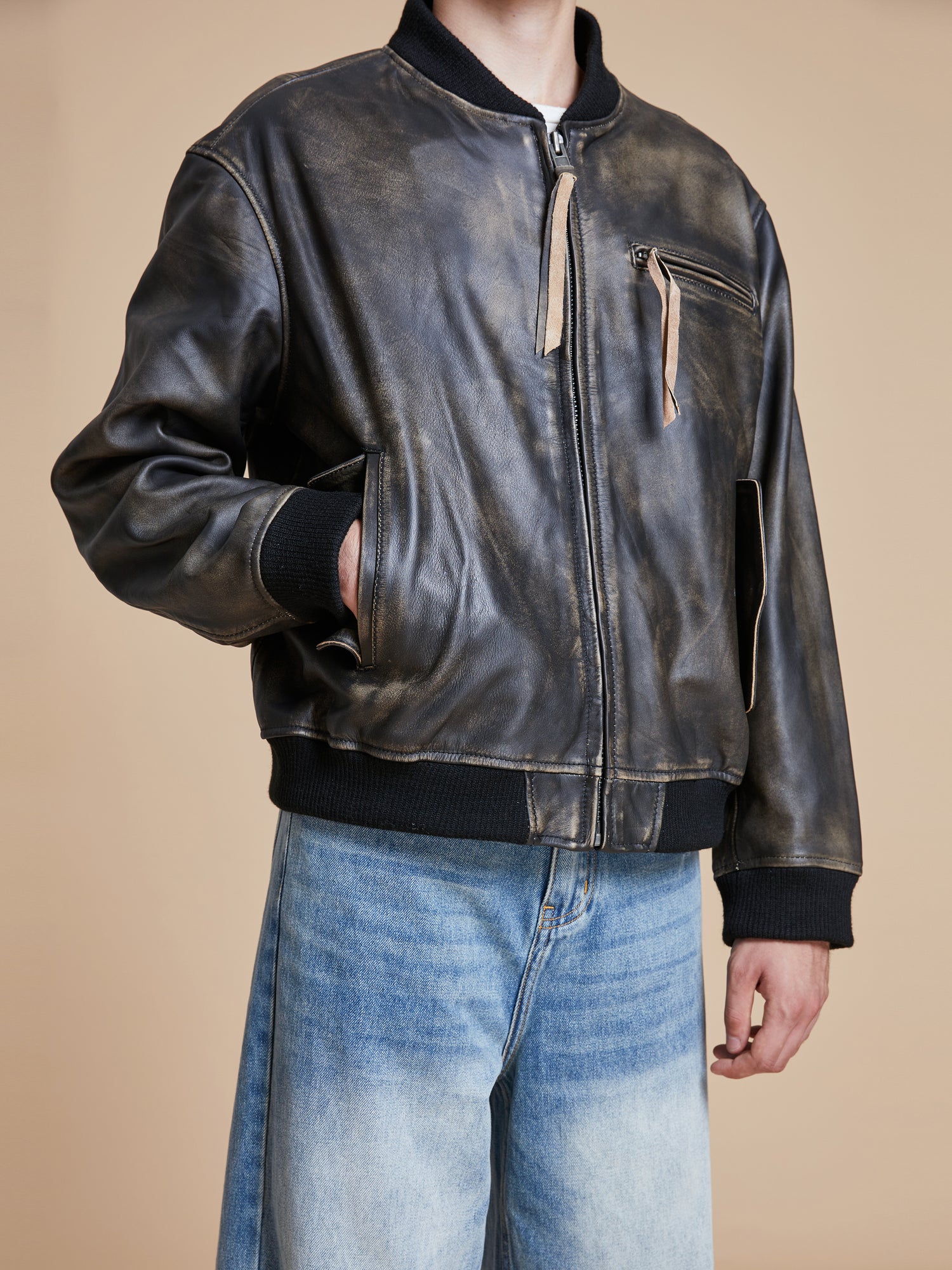 A man wearing a Found Distressed Pavement Leather Bomber Jacket.