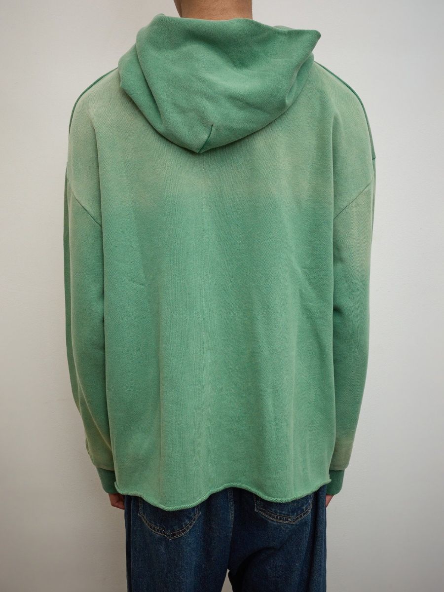 A person is shown from the back against a light background, wearing blue jeans and the FOUND Embroidered Wildlife Hoodie in green (unisex, relaxed fit).