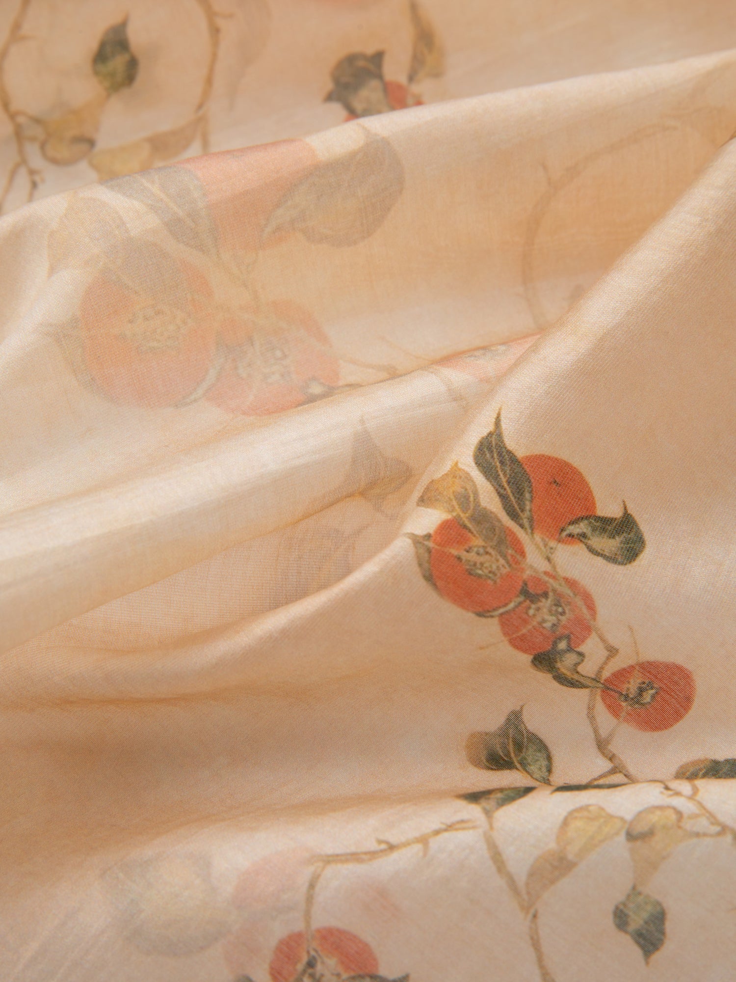 Close-up of the Roshan Floral Bandana by FOUND, showcasing its light beige fabric adorned with a floral pattern featuring red and green flowers and leaves. The material appears soft and slightly translucent.