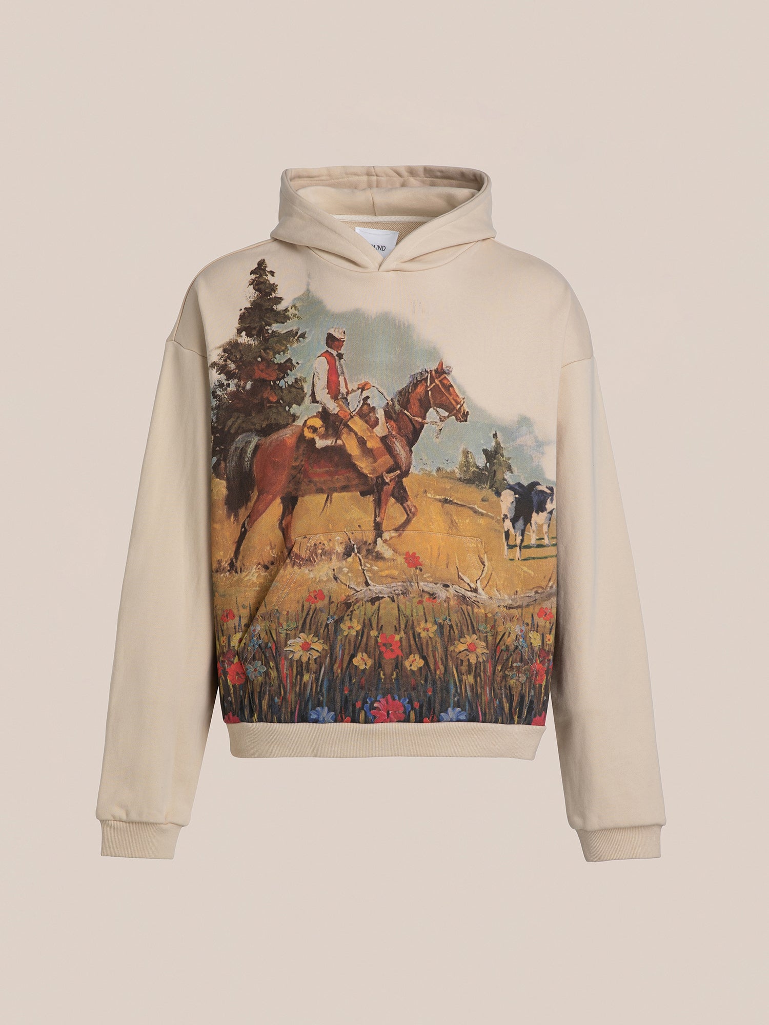 FOUND's Horseman Hoodie in beige boasts a vintage-inspired print of a cowboy on horseback, nestled within a rural landscape adorned with trees and flowers.