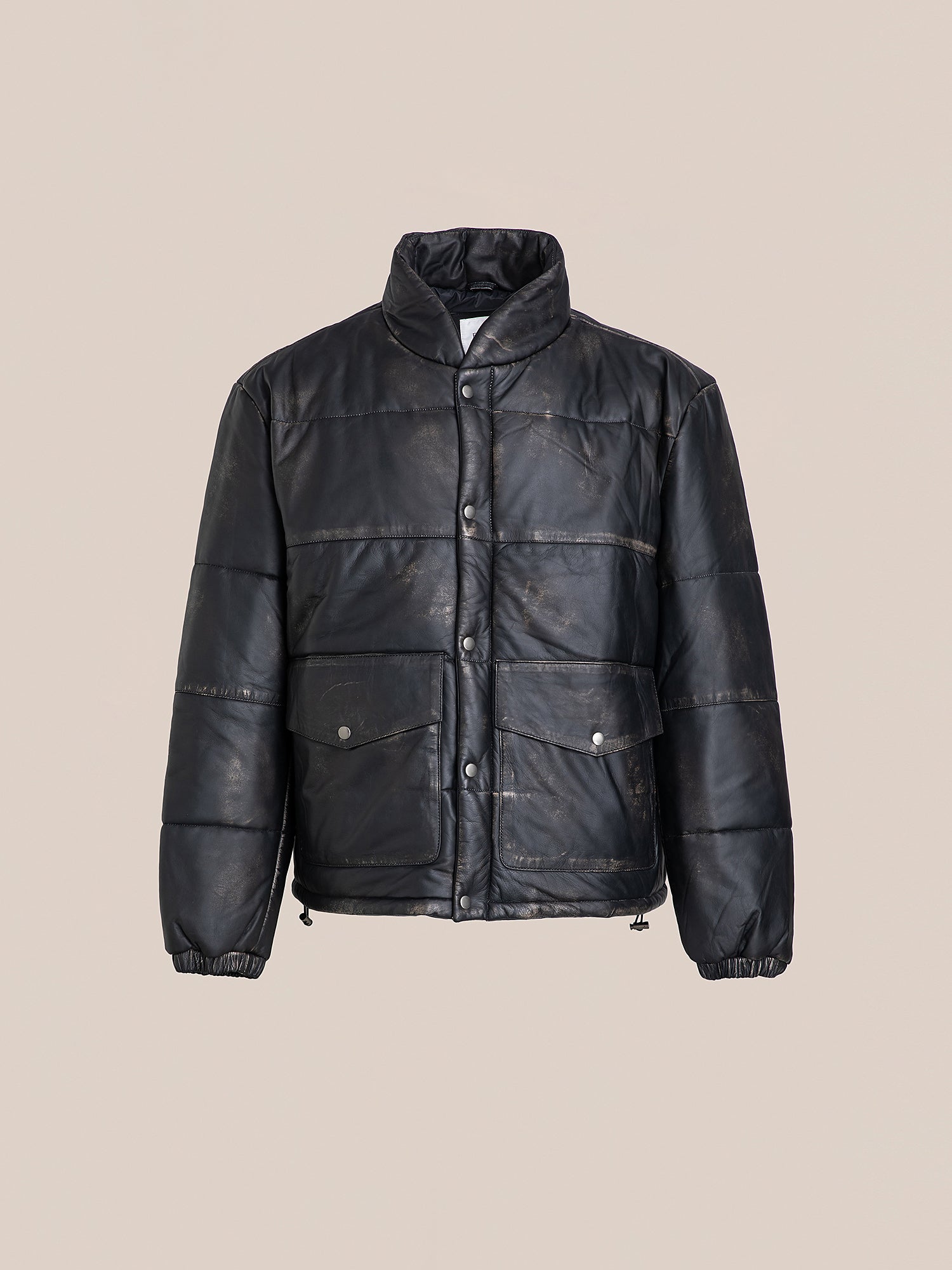 The FOUND Leather Distressed Puffer is a black padded jacket featuring a high collar, button closure, and two front pockets, crafted from ethically sourced materials and presented against a plain background.