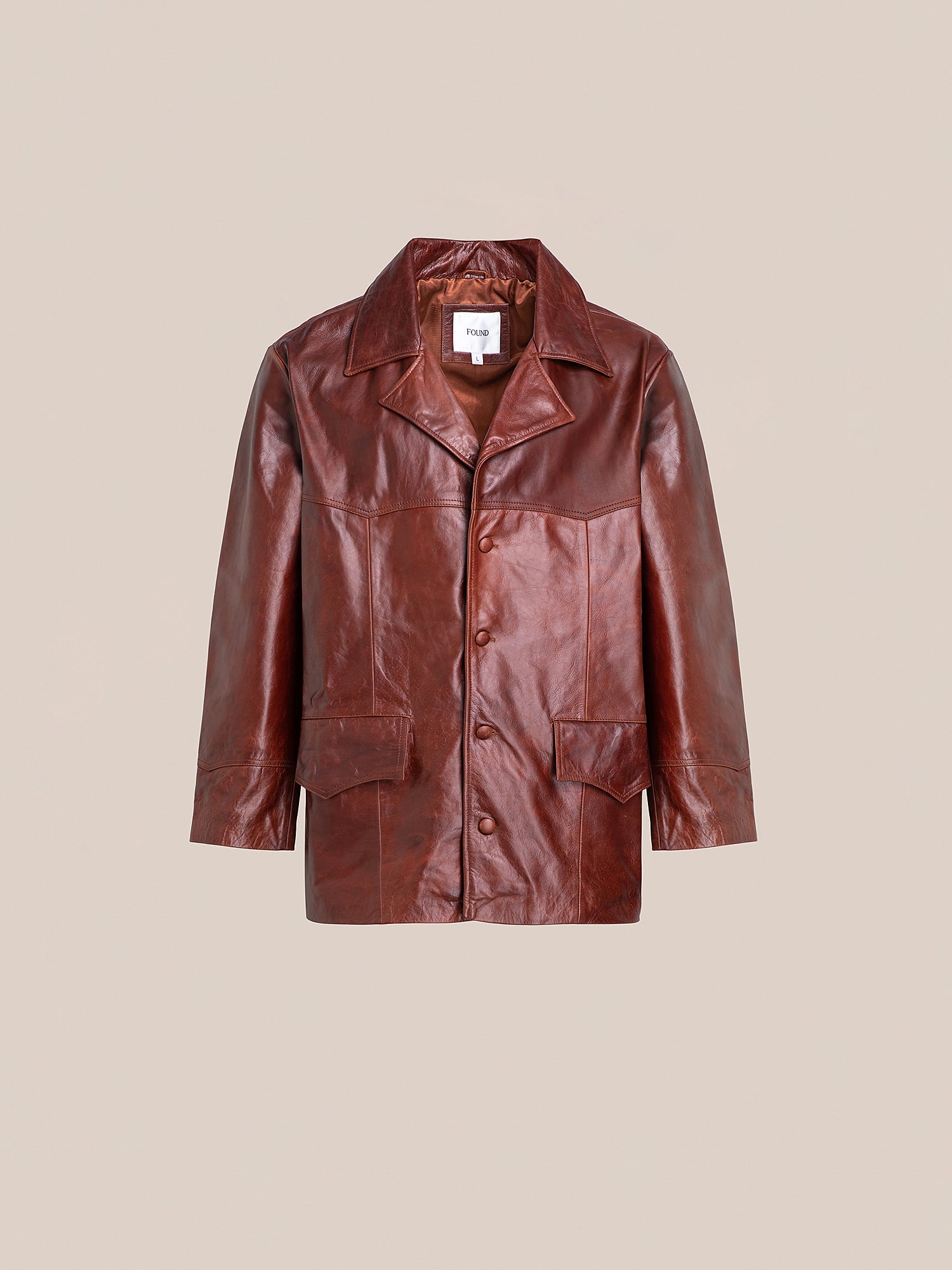 The Claret Western Leather Blazer by FOUND is crafted from ethically sourced, lightweight cowhide. It boasts a rich brown tone, large collar, button closure, and practical front pockets, blending classic style with modern responsibility against a plain backdrop.