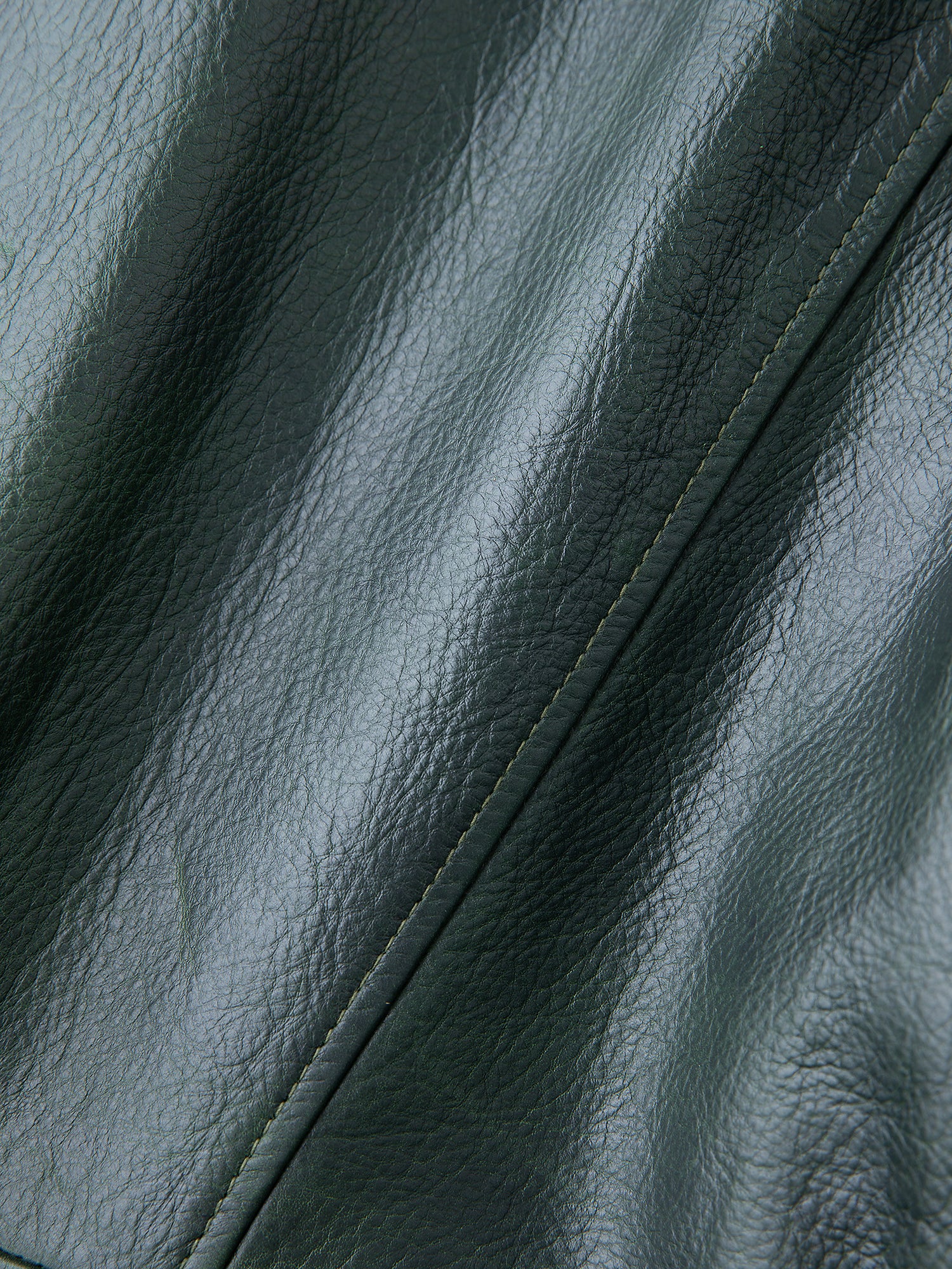 Close-up of the FOUND Emerald Leather Jacket in dark leather, showcasing its textured surface and intricate stitching.