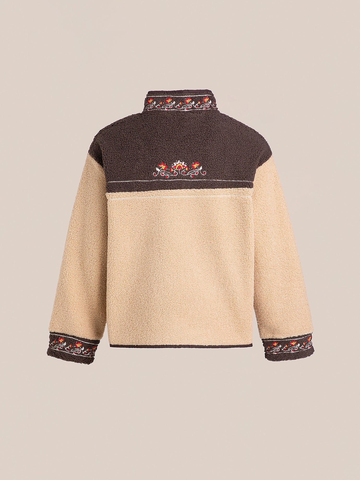 The back view of the FOUND Pahari Floral Embroidered Sherpa Pullover showcases intricate floral embroidery, with a beige lower section, a dark upper portion, and elegant designs embellishing the collar, back, and cuffs.