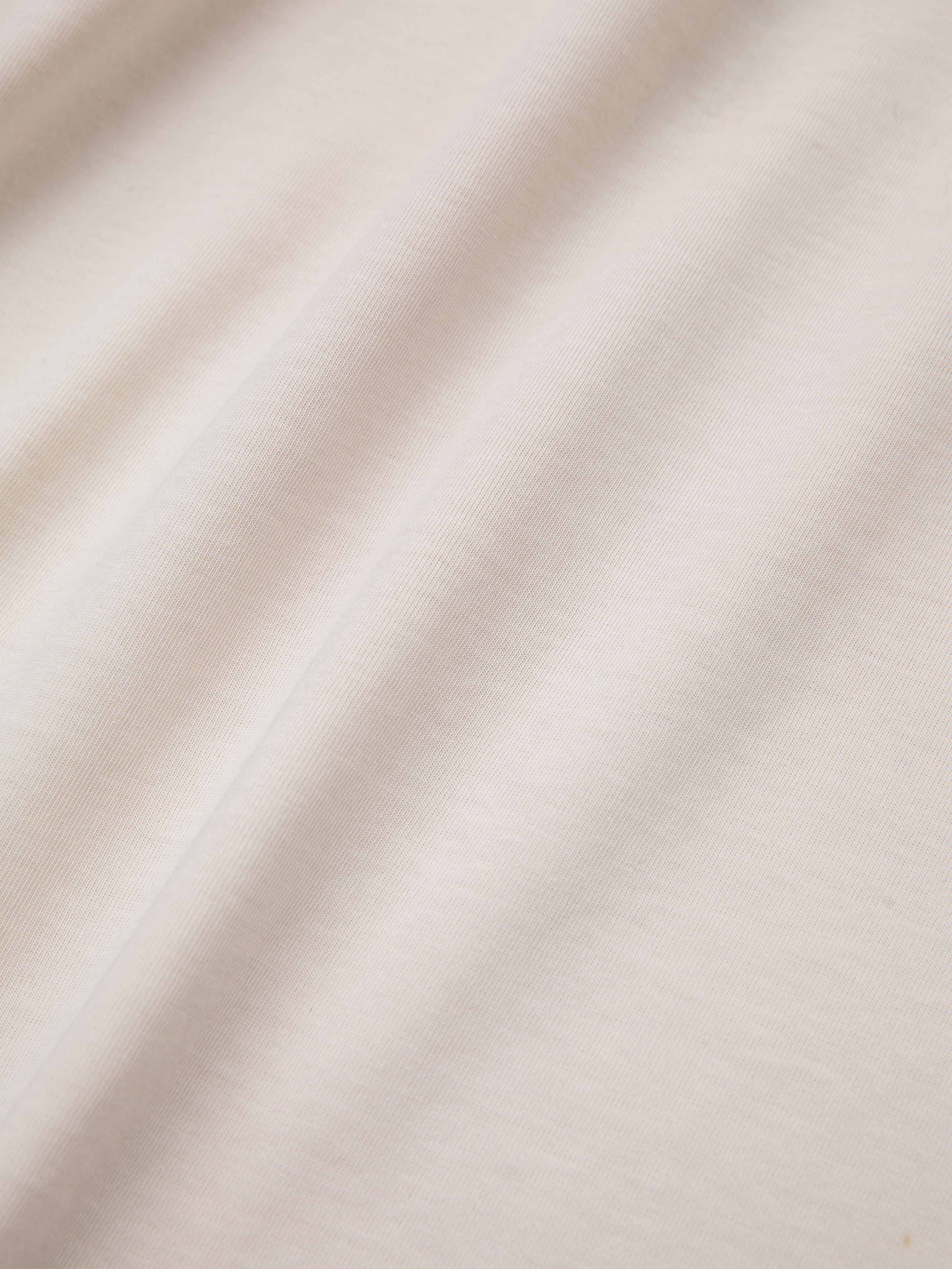 Close-up of the Urdu Graphic Tee by FOUND, featuring cream-colored fabric with soft folds and a smooth texture, reminiscent of the elegance found in Mughal paintings.