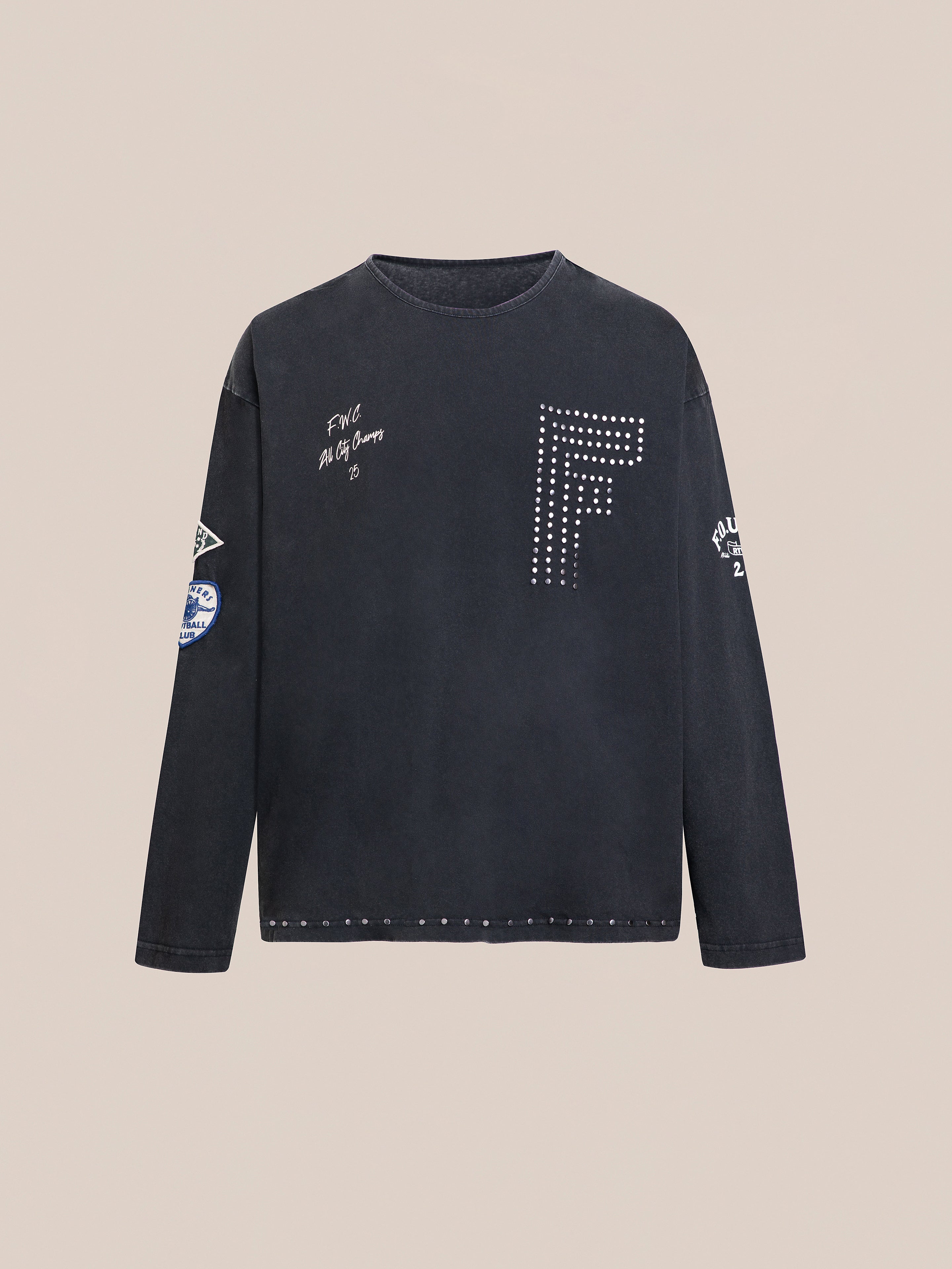 FOUND's Studded LS Shirt features a black long-sleeve design with a prominent studded "F" and is adorned with several white graphic patches and text details on both the front and sleeves.