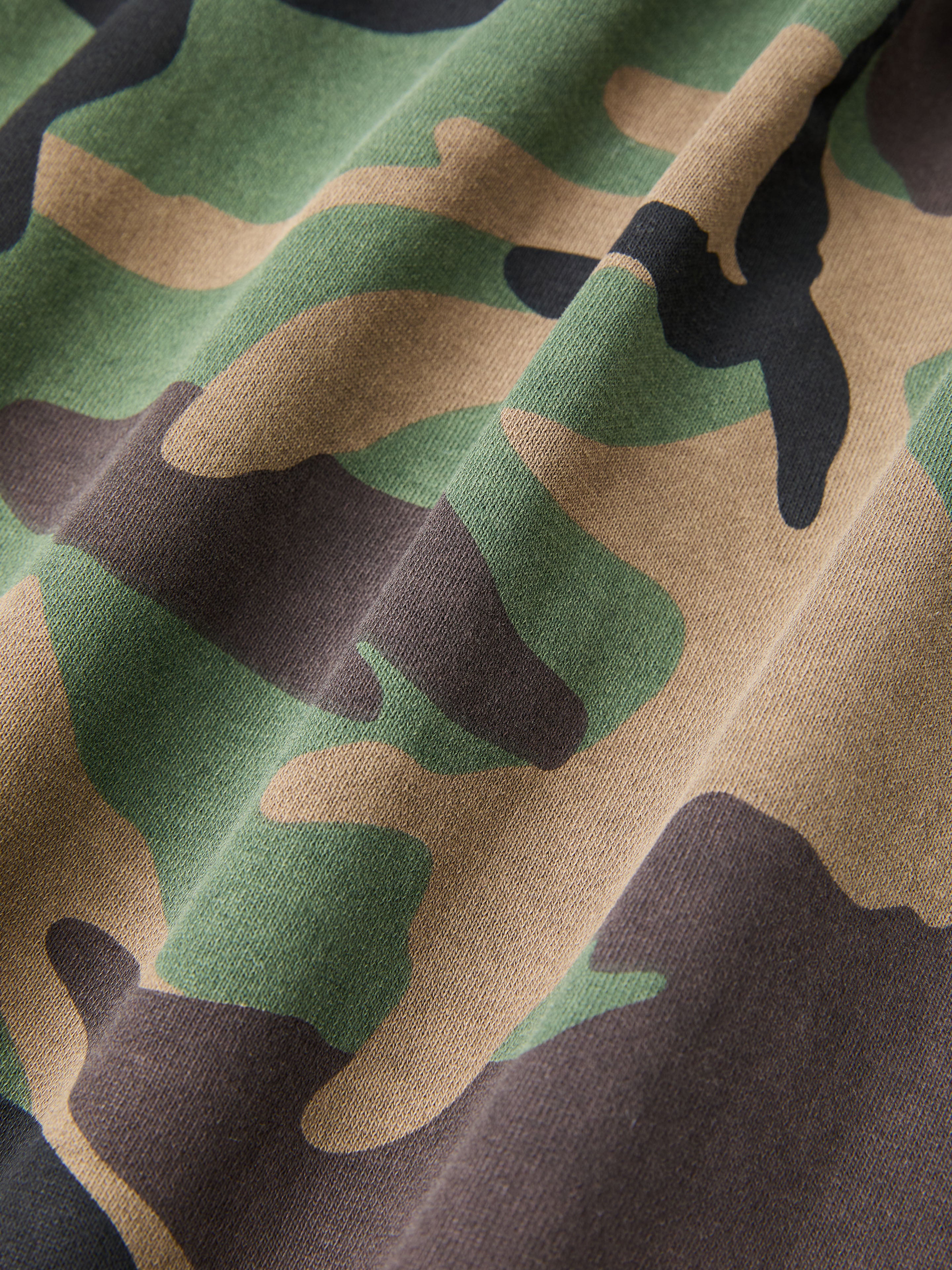 Close-up of the FOUND Camo Zip Hoodie, a unisex design featuring a classic green, brown, khaki, and black camouflage print.