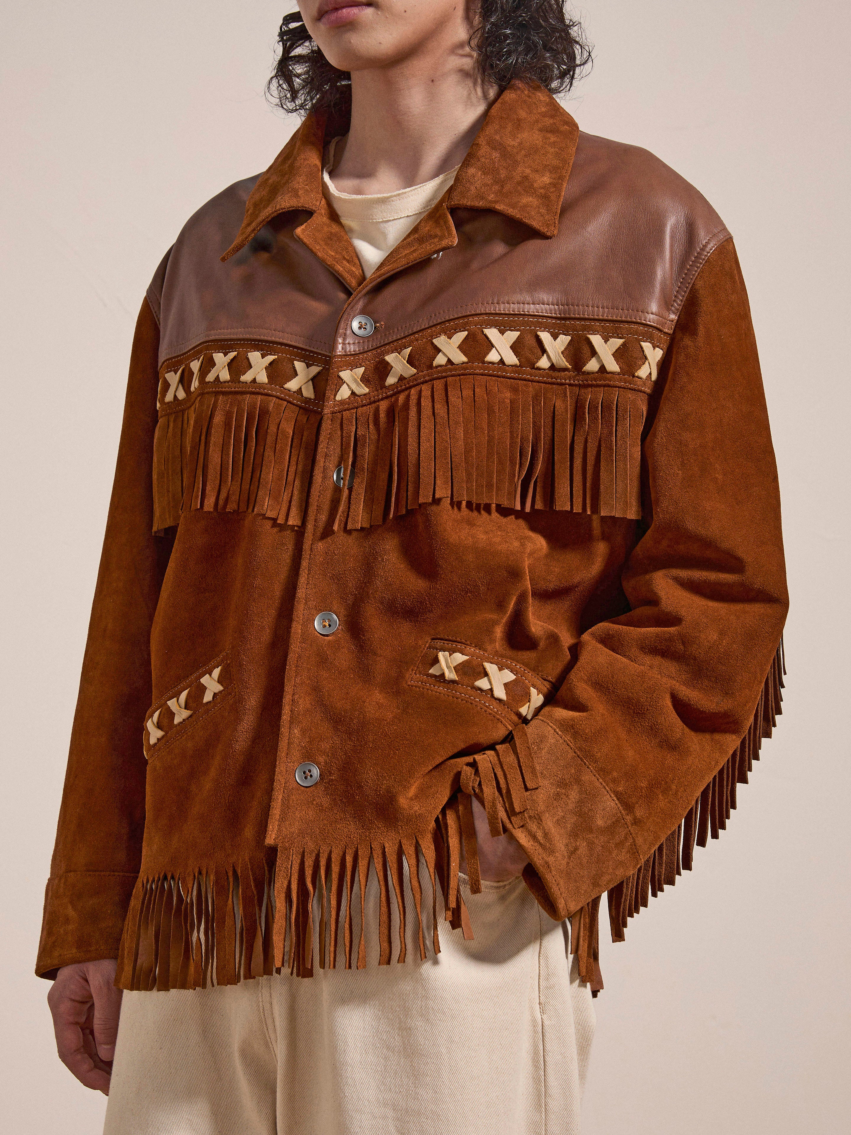 Person wearing a FOUND Western Fringe Suede Jacket with leather accents and fringe details, paired with beige pants, standing against a plain background.