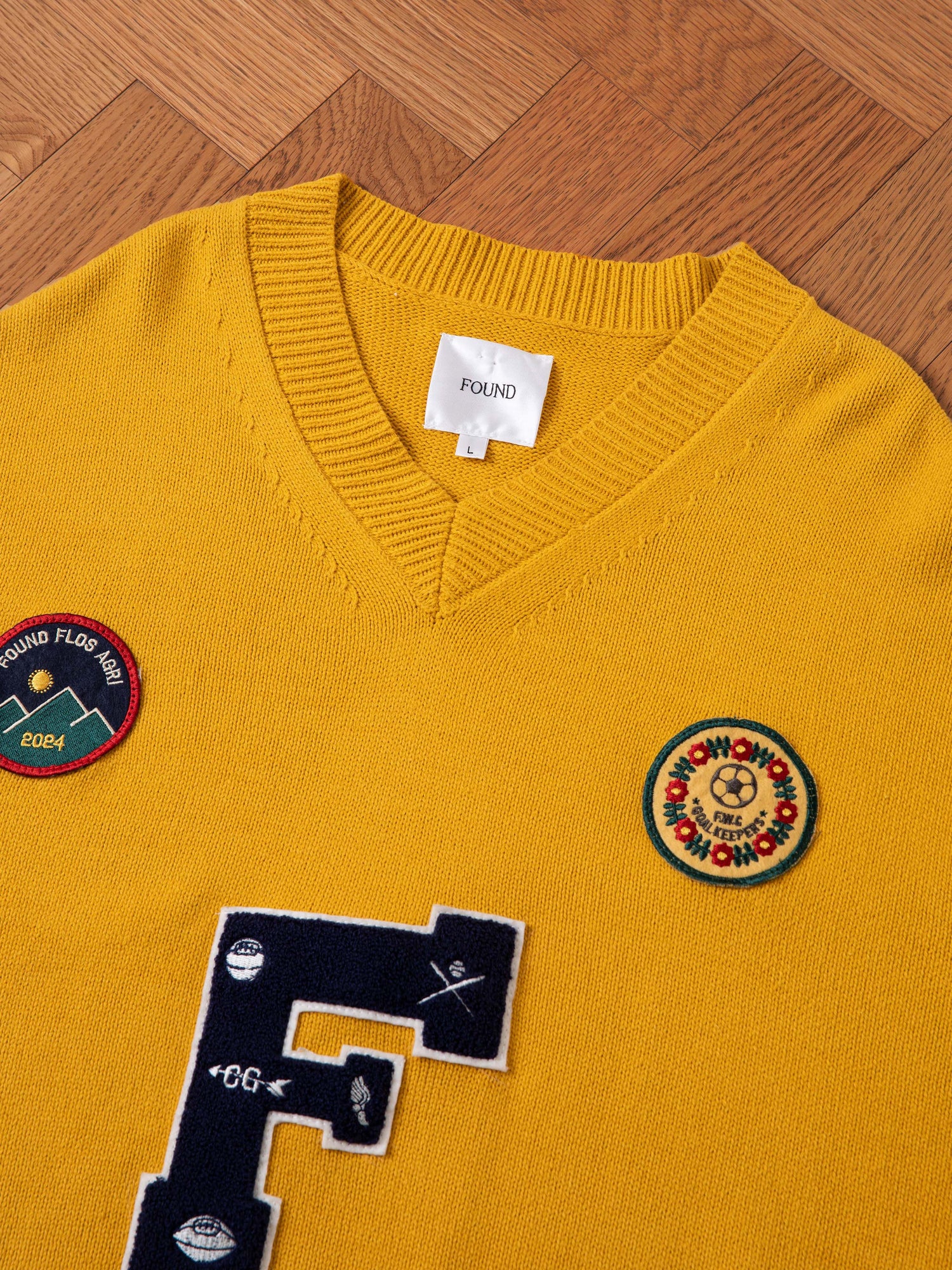 An Arrow-Wood Varsity Knit Sweater in yellow, featuring a white label with 