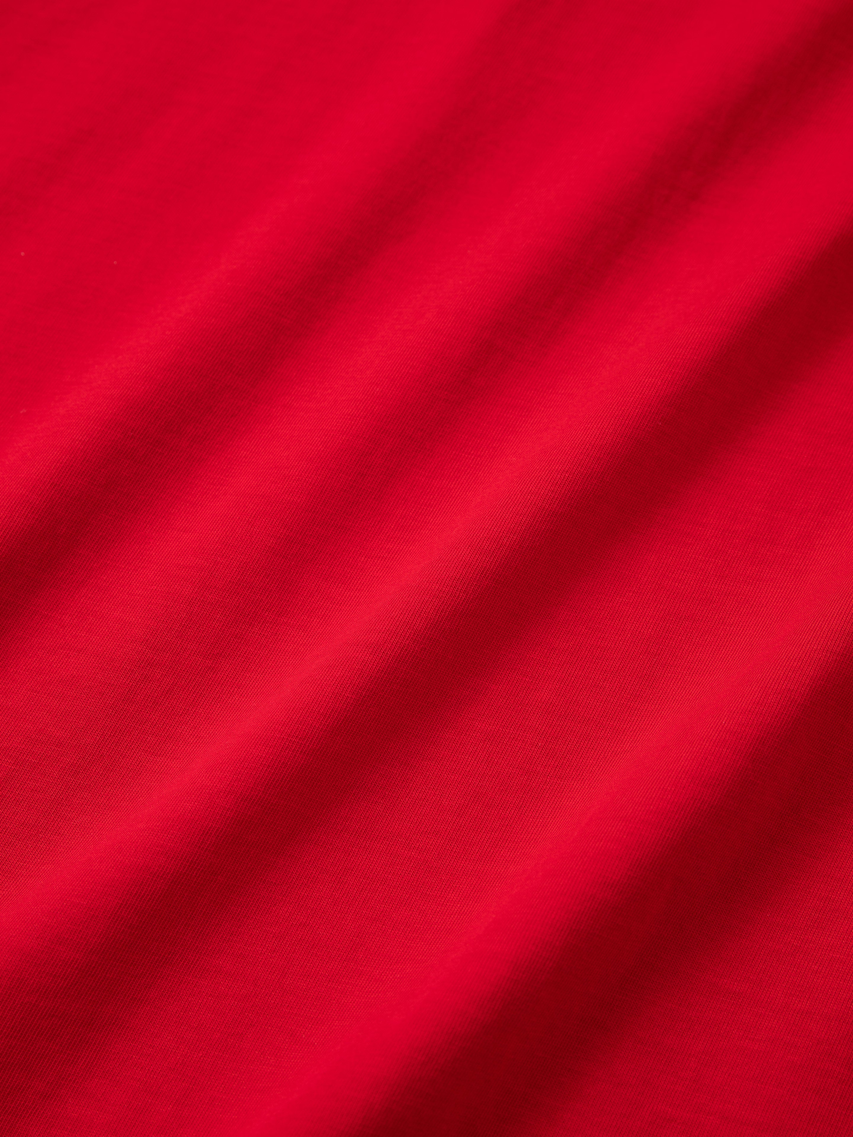 Close-up of the Goji Red Jersey by FOUND, showcasing its smooth, slightly wrinkled texture, reminiscent of vintage athletic uniforms.