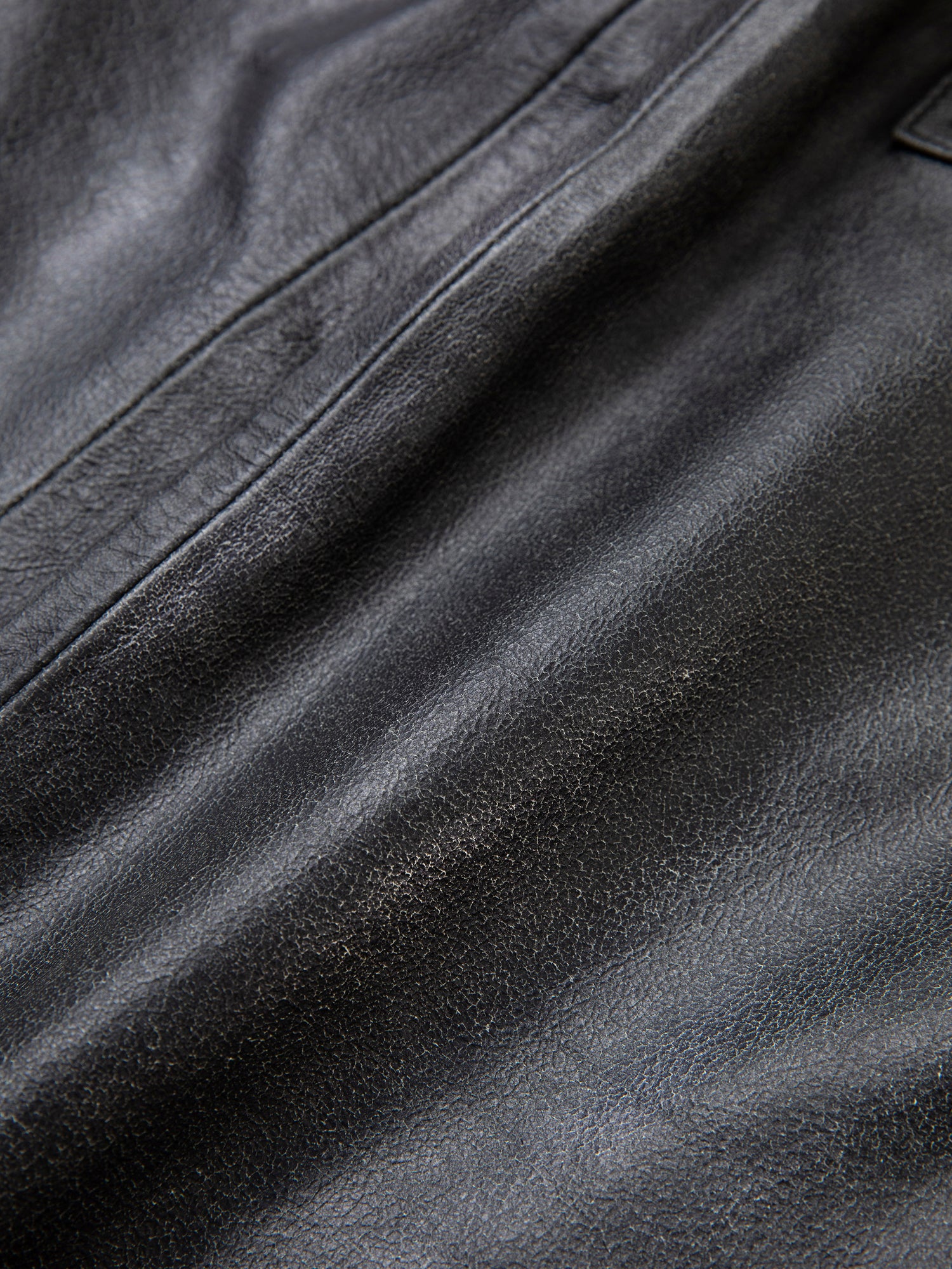 Close-up of a black leather surface showing its texture and natural creases, reminiscent of the quality found in an ethically sourced Distressed Genuine Leather Pocket Vest by Found.