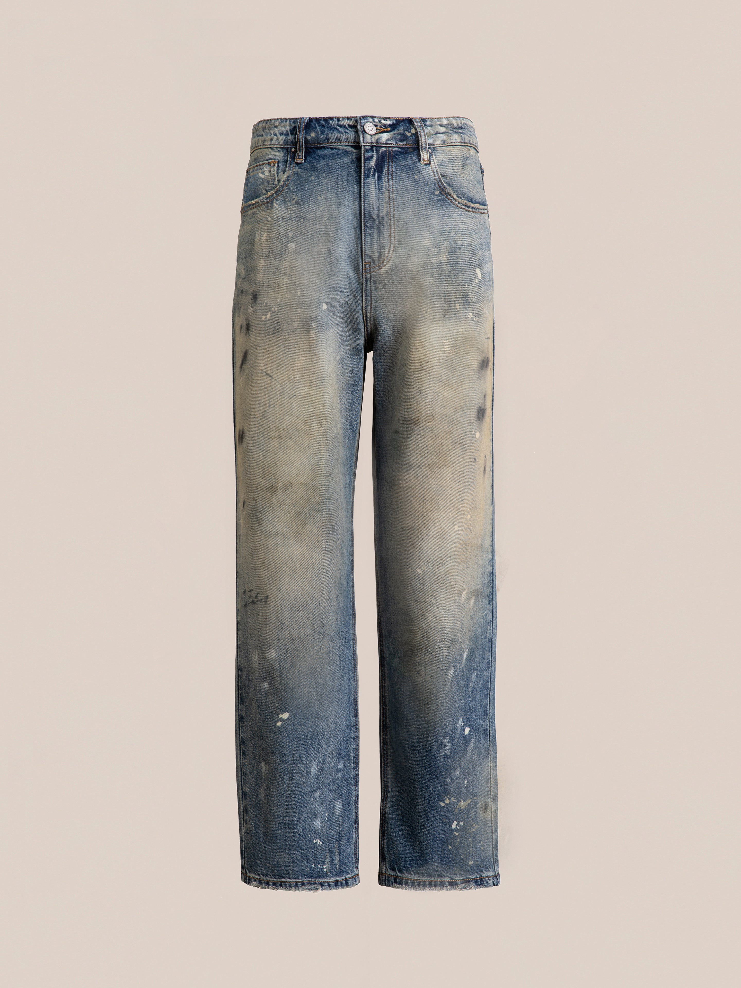 FOUND Monet Paint Jeans: Experience timeless style with worn and faded blue jeans, showcasing a vintage blue wash. The hand-painted splatter and distressed details stand out beautifully against a light brown background.