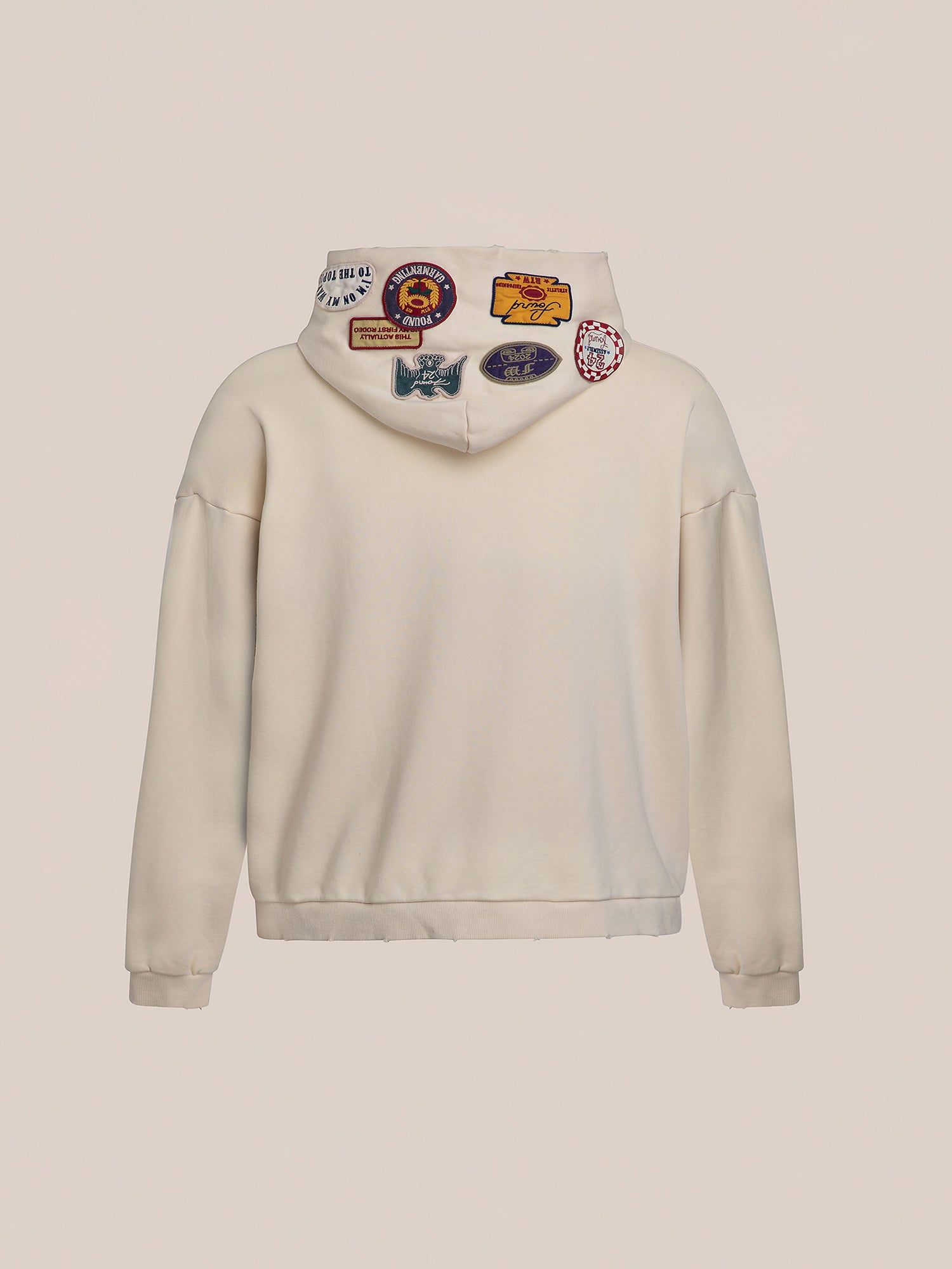 Rear view of the Faded Patch Hoodie by FOUND, showcasing its oversized fit and a variety of colorful patches on the hood for a vintage appeal.