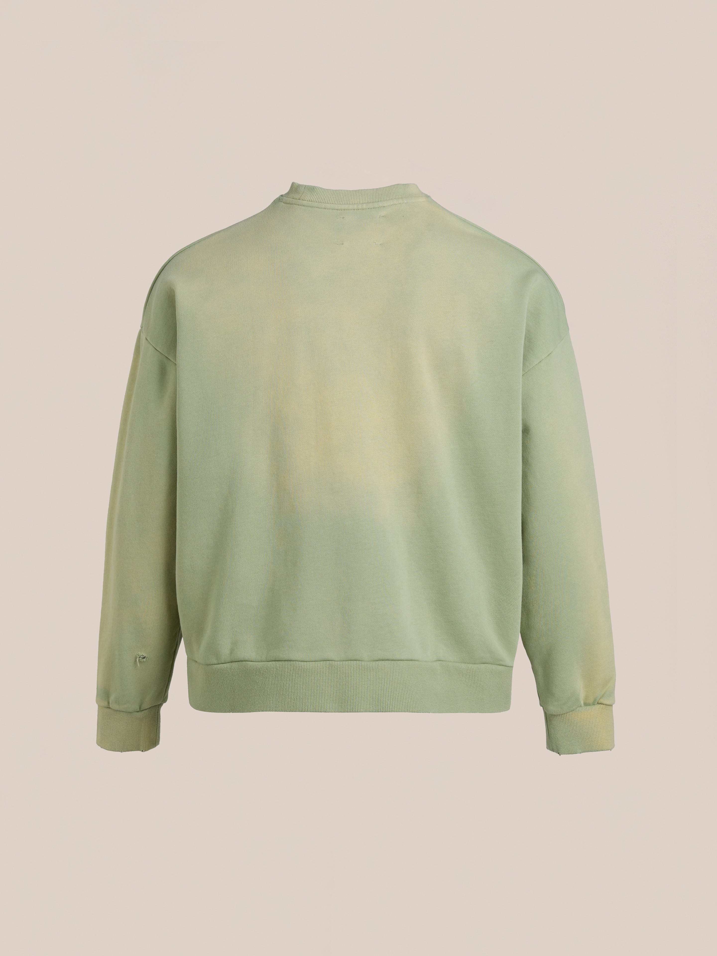 Back view of the Faded Pocket Crewneck from FOUND, a light green sweatshirt in heavyweight cotton with long sleeves, ribbed neckline, cuffs, and hem. This unisex relaxed fit piece exudes vintage-inspired style against a plain backdrop.