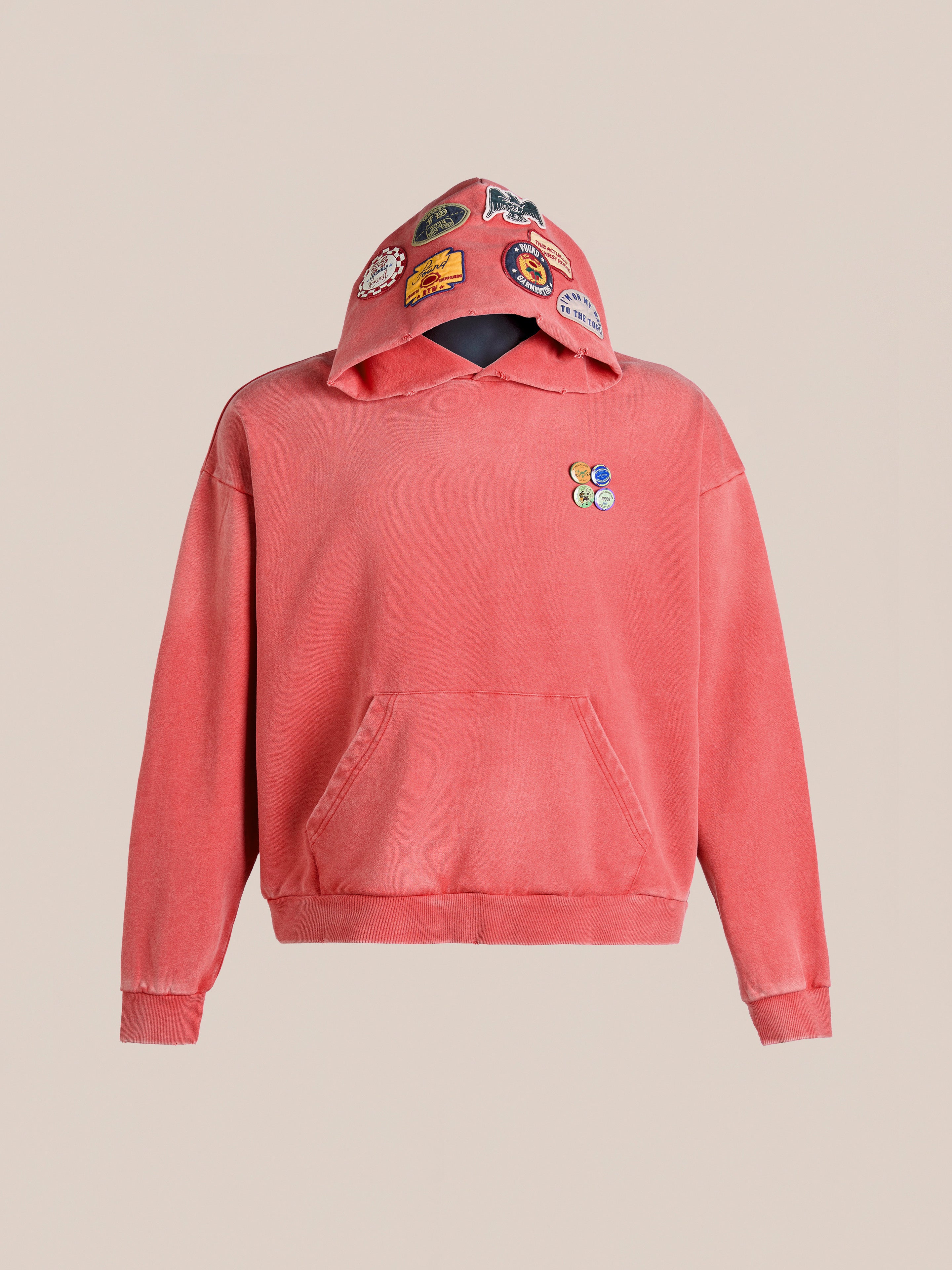 FOUND's Multi Patch Hoodie is a vintage-inspired red hoodie featuring a front pocket, small embroidered chest logos, and colorful hood patches, embodying nostalgic charm.