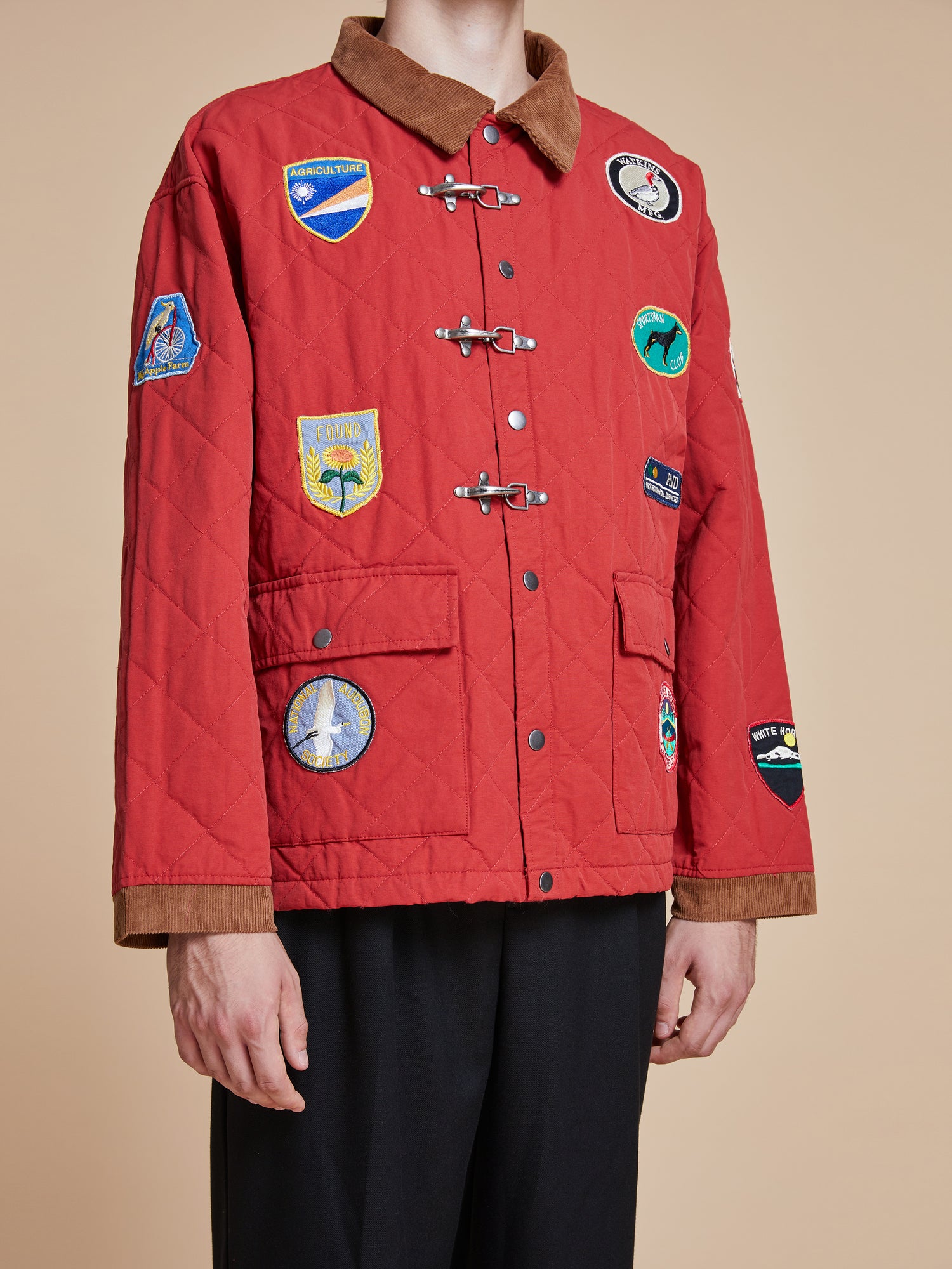A man wearing a Found Farmstead Quilt Patch Jacket with patches.