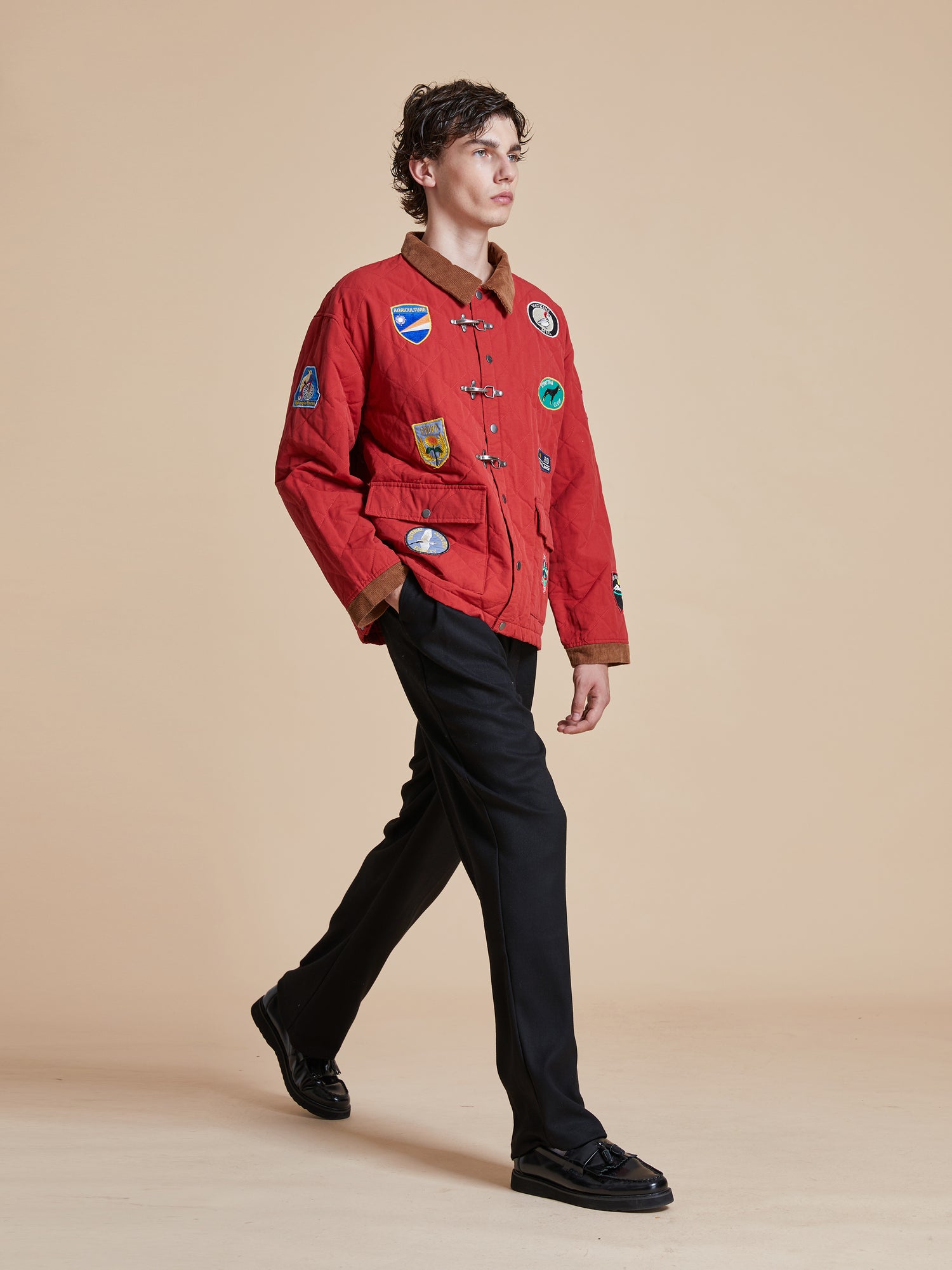 A man wearing a Farmstead Quilt Patch Jacket by Found and black pants.