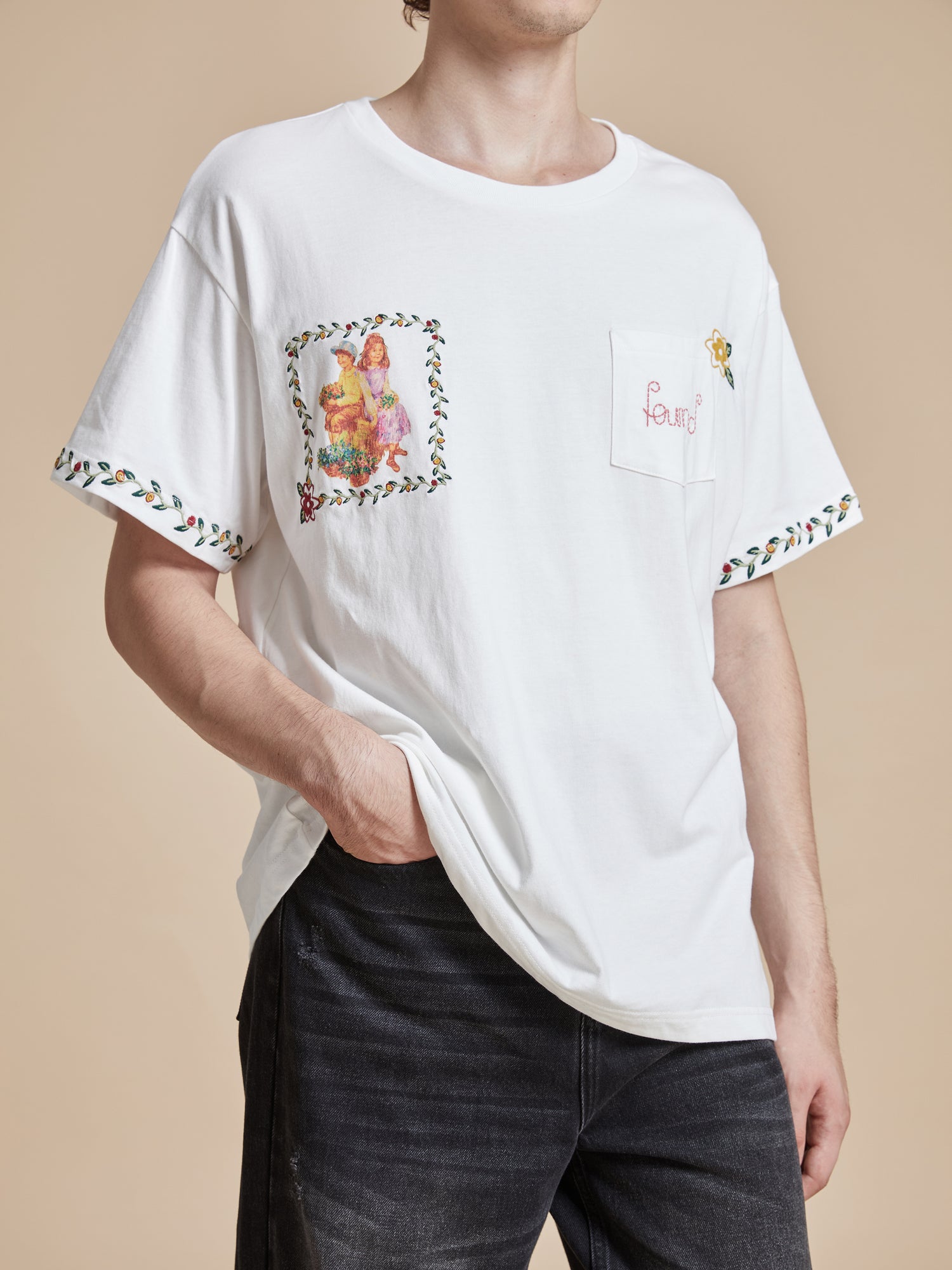 A man wearing a Found Flower Children Tee with floral Phulkari style embroideries, inspired by classic American folk art.