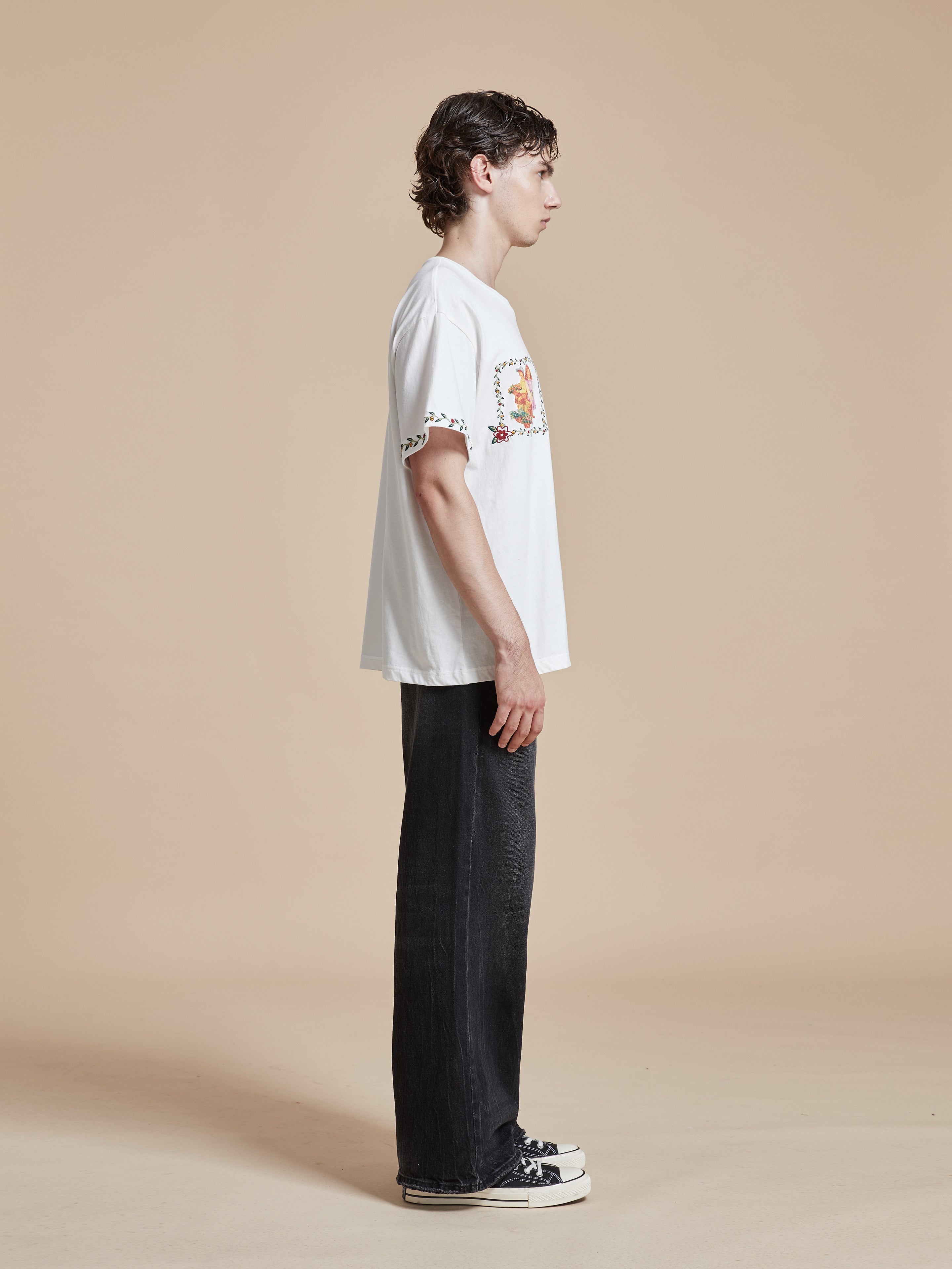 A man wearing a white Flower Children Tee with floral Phulkari style embroideries by Found.