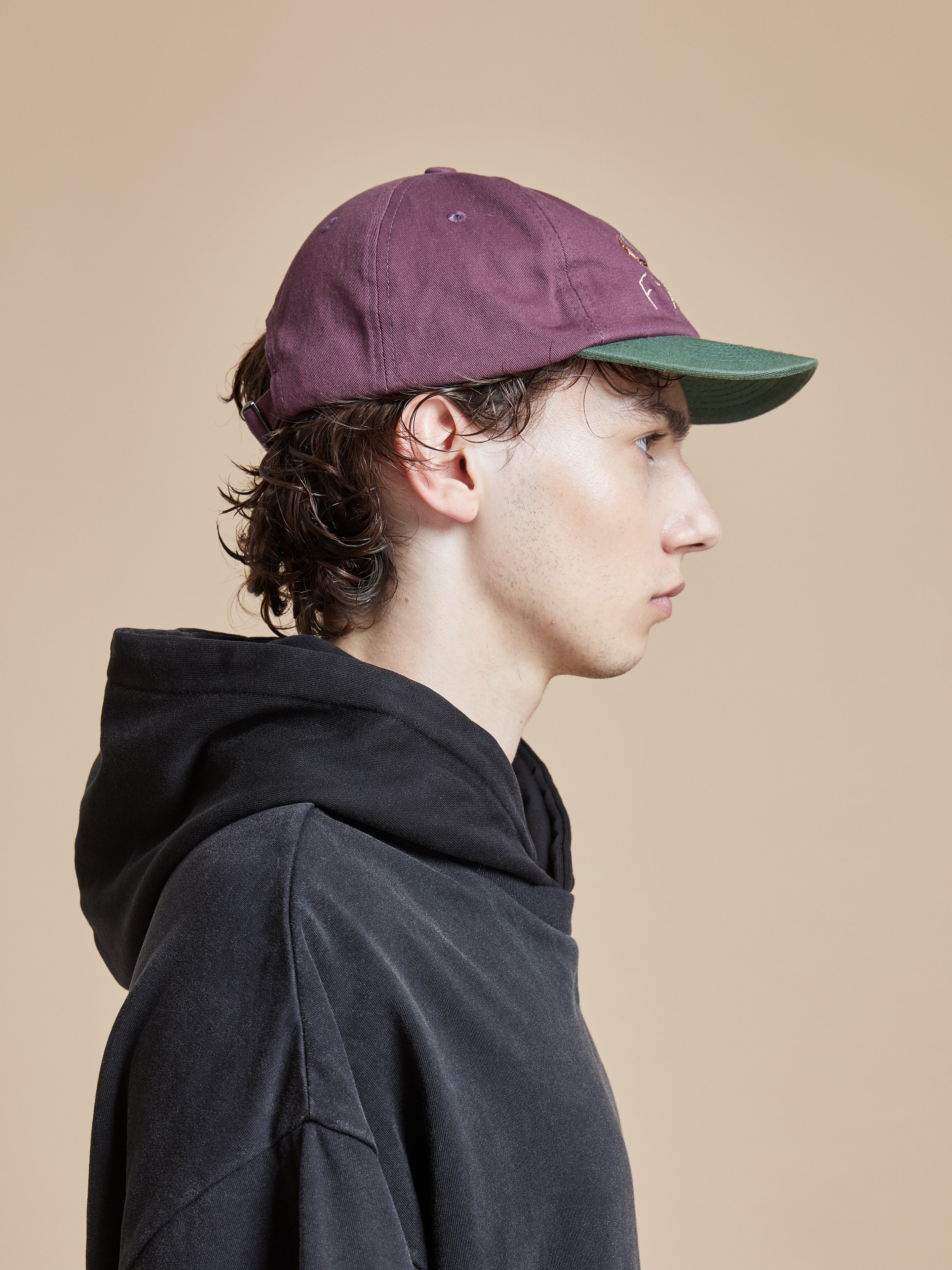 A man wearing a Flower Deer cap and a burgundy hoodie.