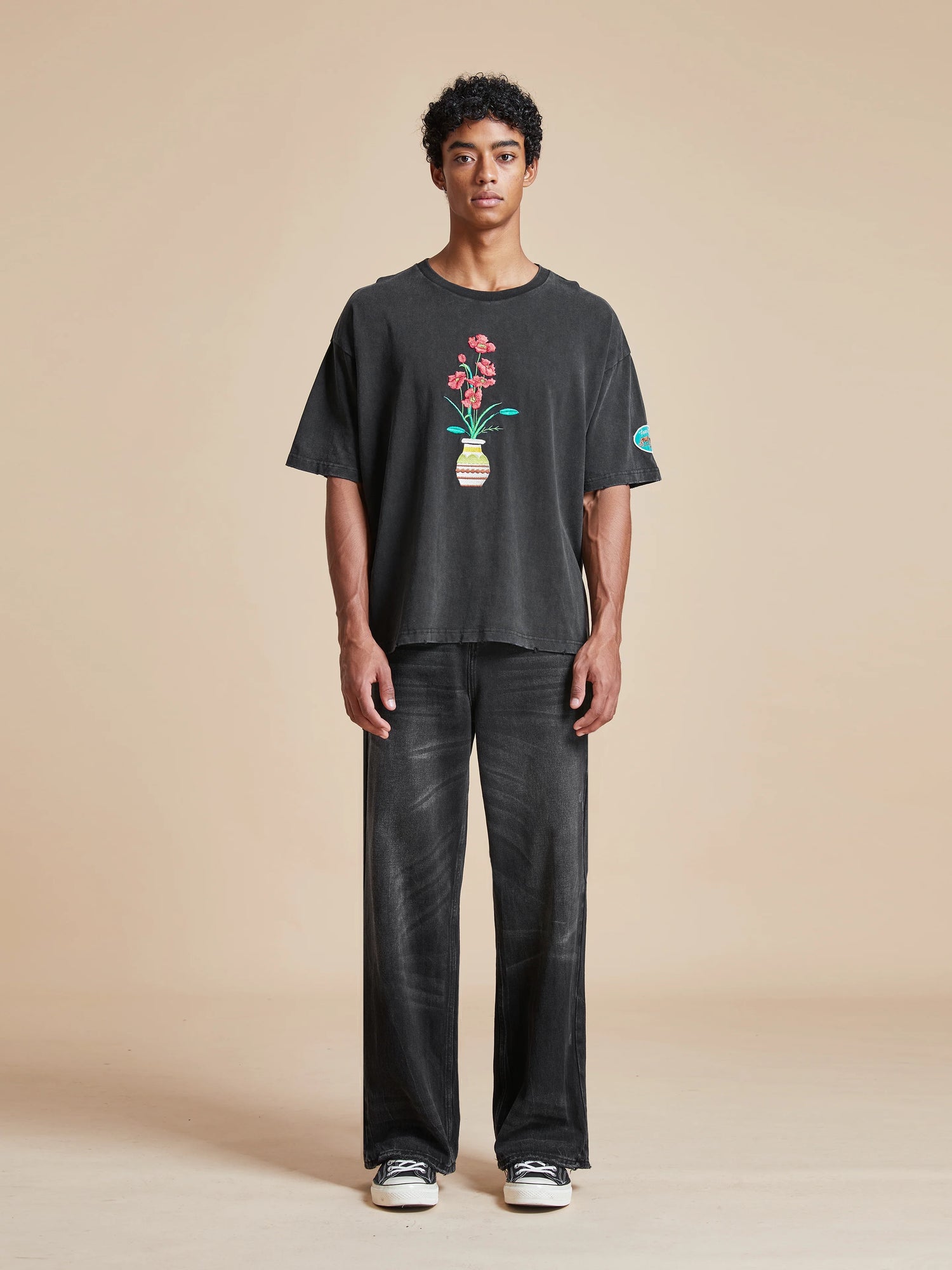 A man wearing a black t-shirt with a Flowers Vase Tee embroidered using Phulkari embroidery by Found.