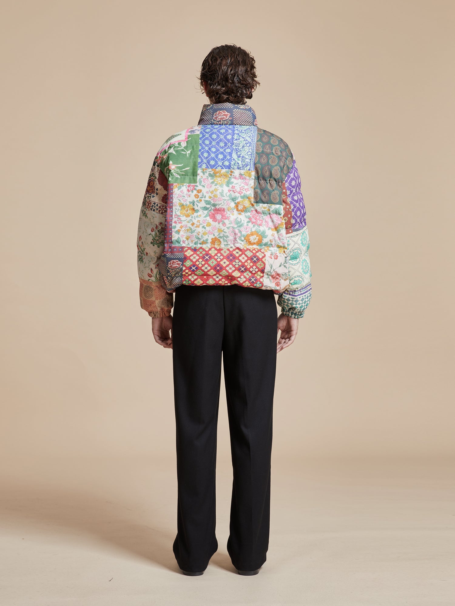 The back of a man wearing a Found Gardenia Tapestry Puffer Jacket, showcasing traditional South Asian prints.