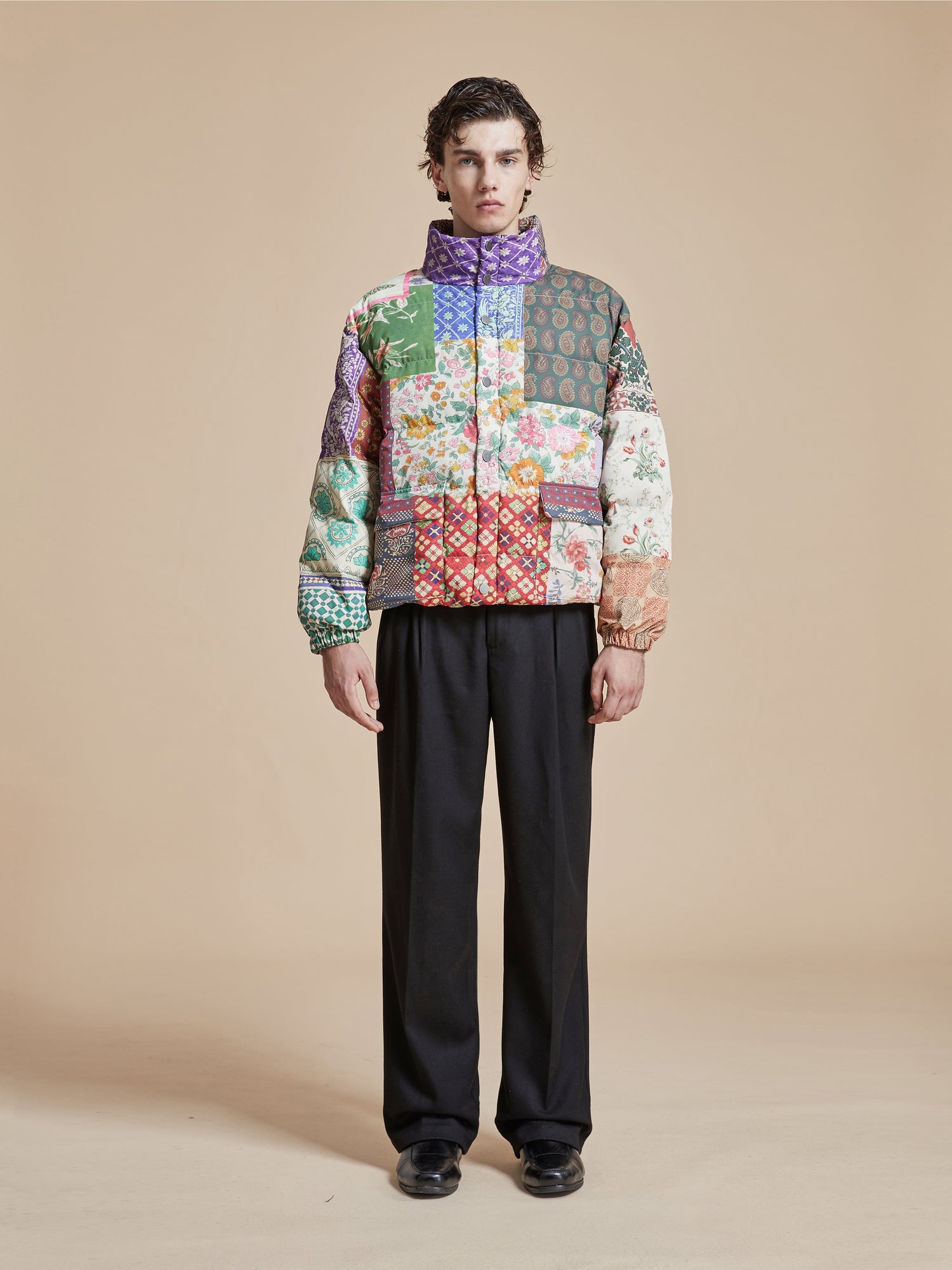 A man wearing a Found Gardenia Tapestry Puffer Jacket adorned with traditional South Asian prints.