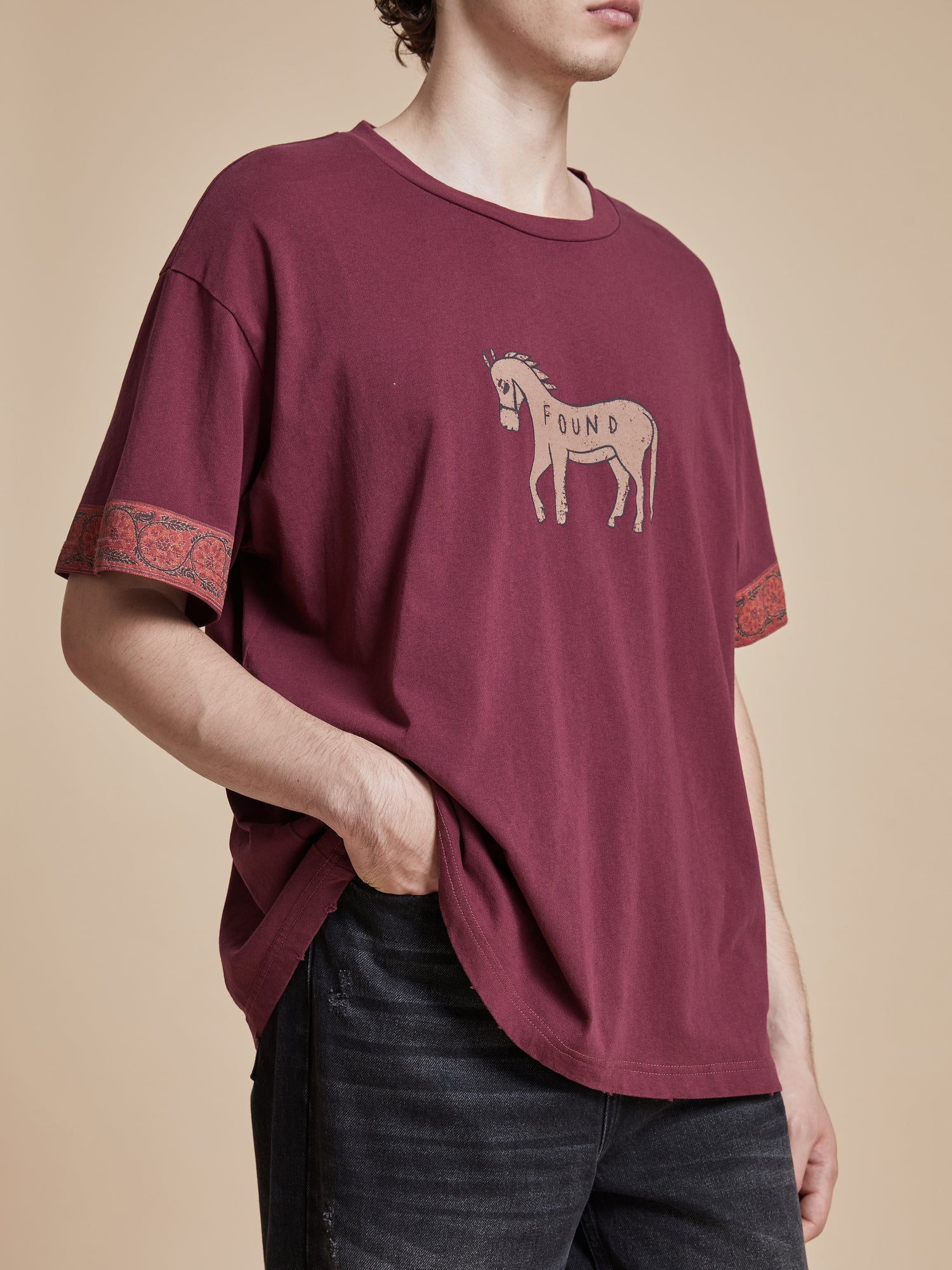 A man wearing a burgundy Horse Embellishment Tee from Found.