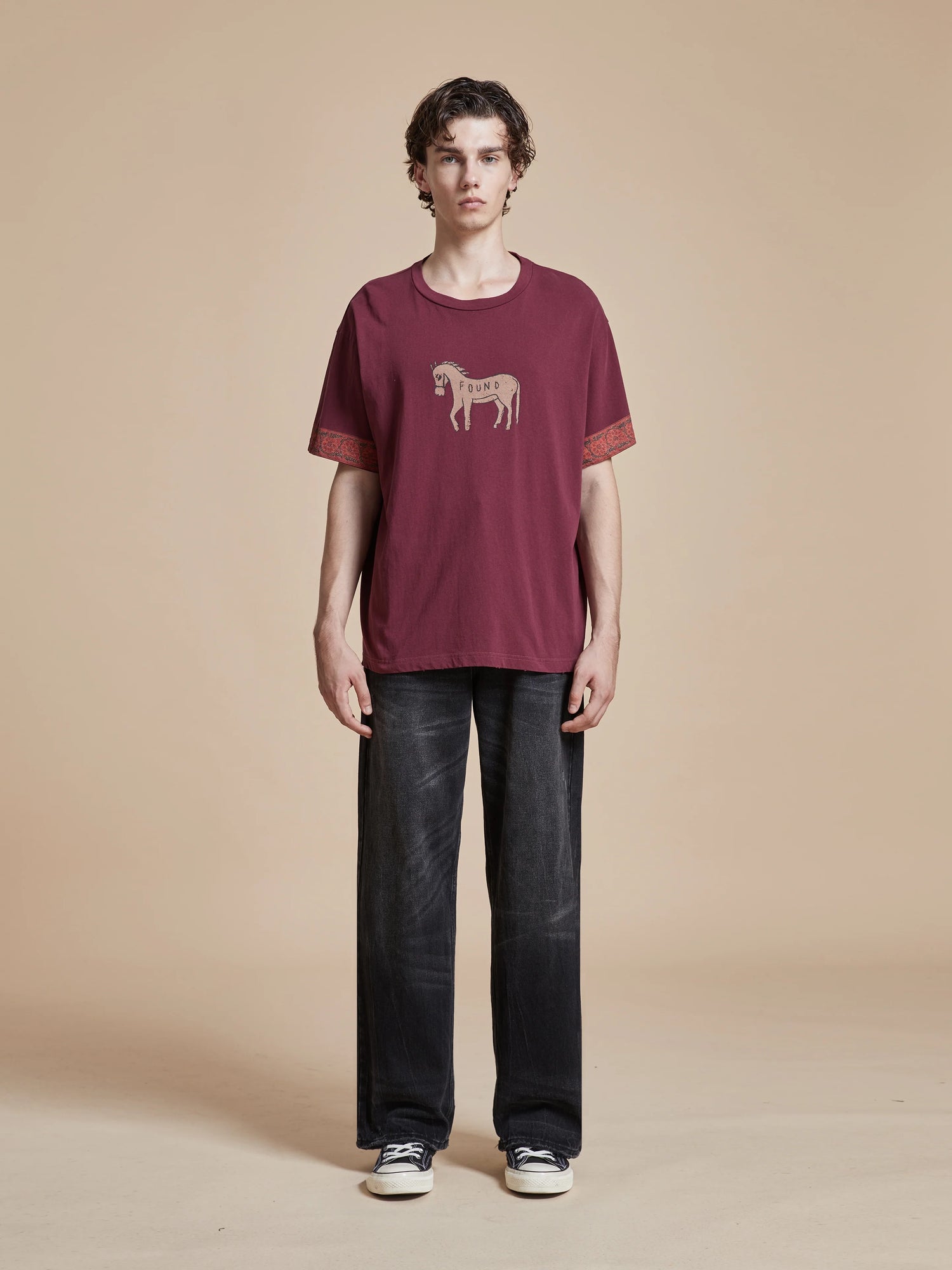 A man wearing a faded purple wash Horse Embellishment Tee by Found.