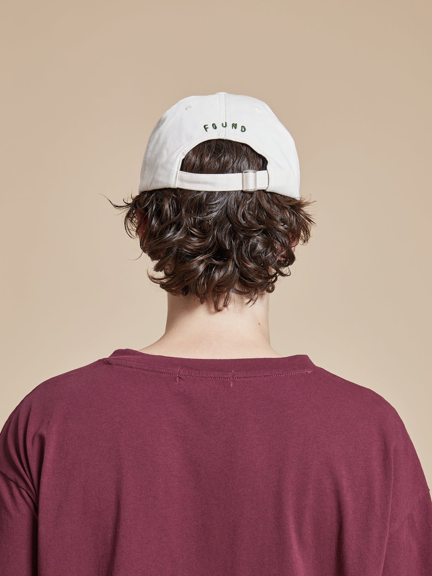 The back view of a man wearing a burgundy t-shirt and a Found Horse Equine Cap.
