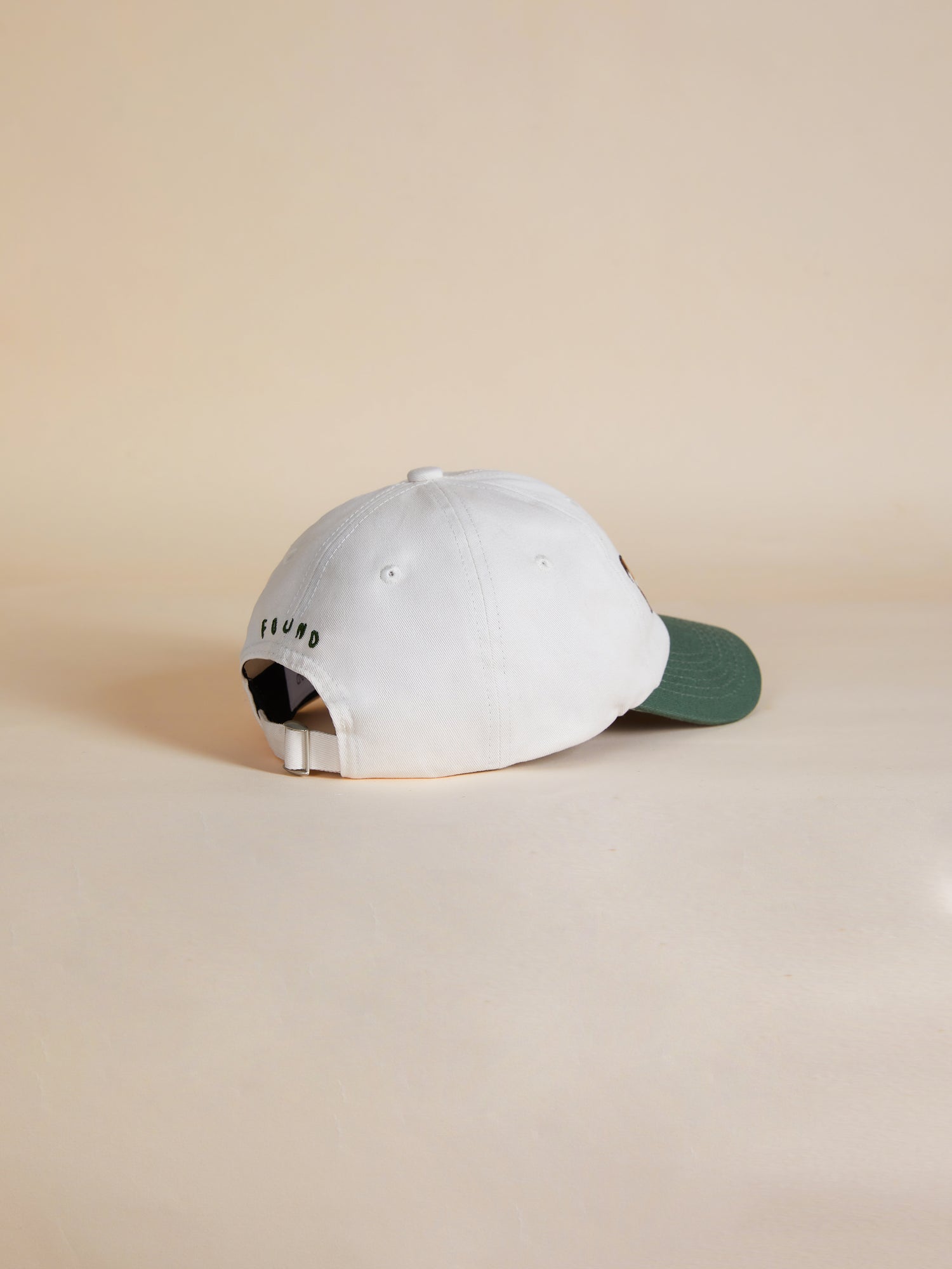 A white and green Horse Equine Cap by Found on a beige surface.