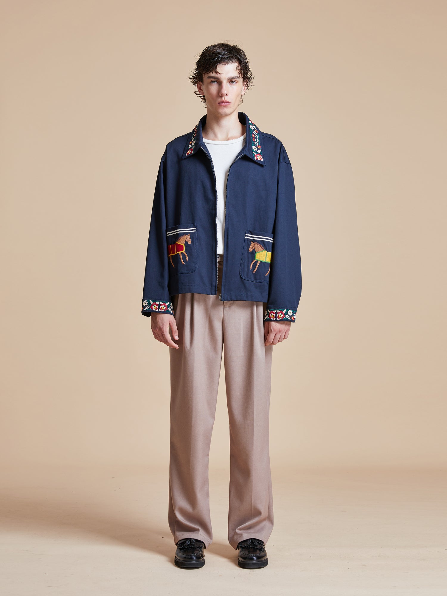 The model is wearing a Found Horse Equine Work Jacket and beige pants.