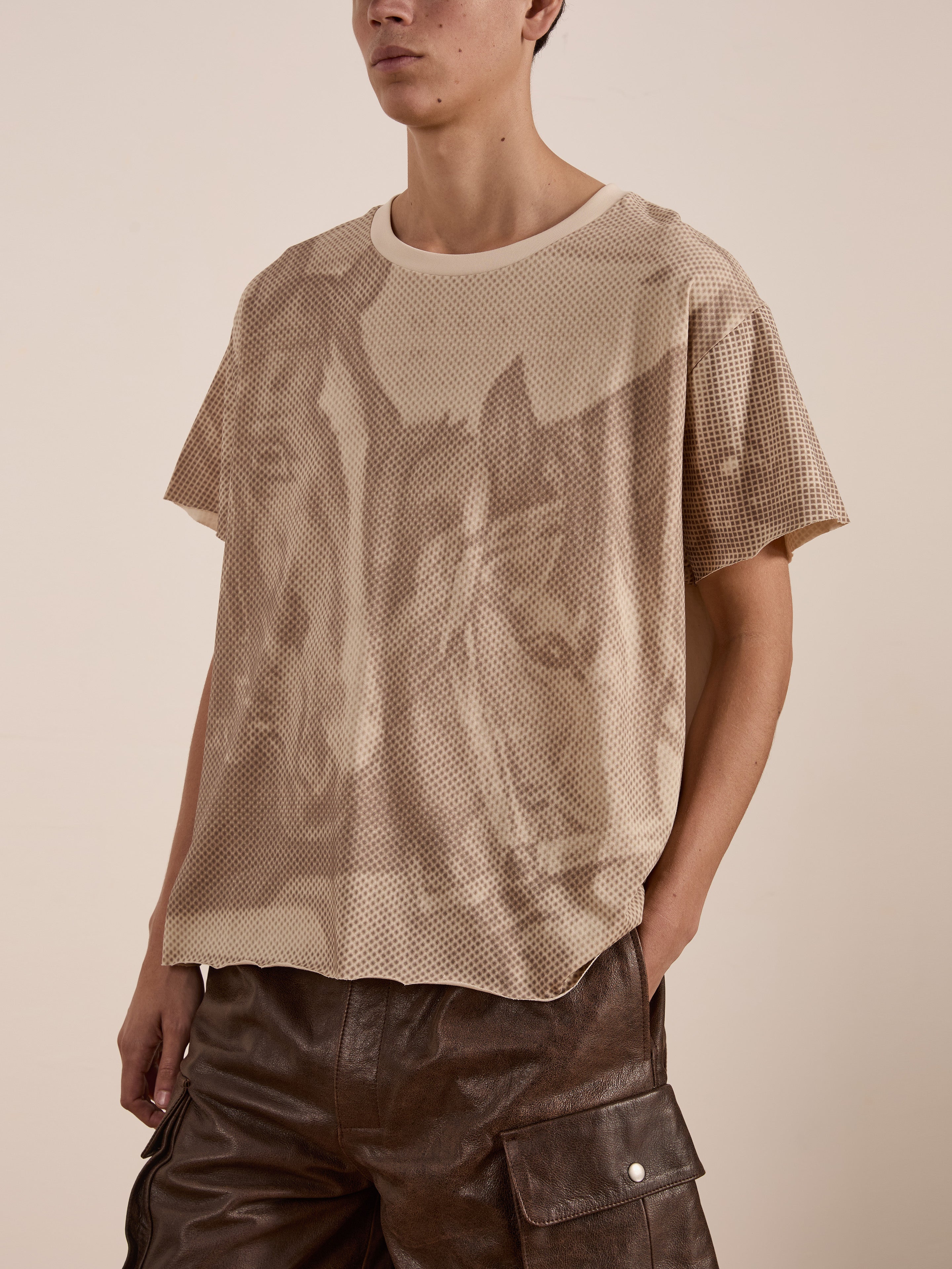 A person wearing a beige mesh FOUND Horse Racer Tee and brown leather pants with pockets portrays an effortlessly stylish look.