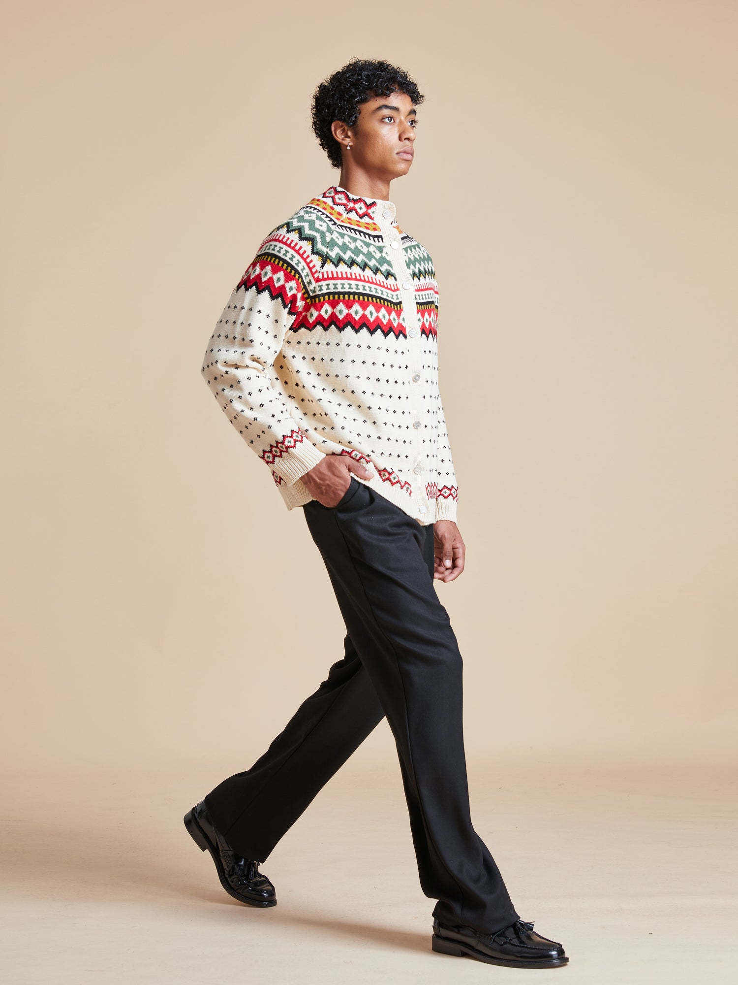 A man in a Harwan Isles Sweater walking on a beige background, pre-order option available. (Brand Name: Found)