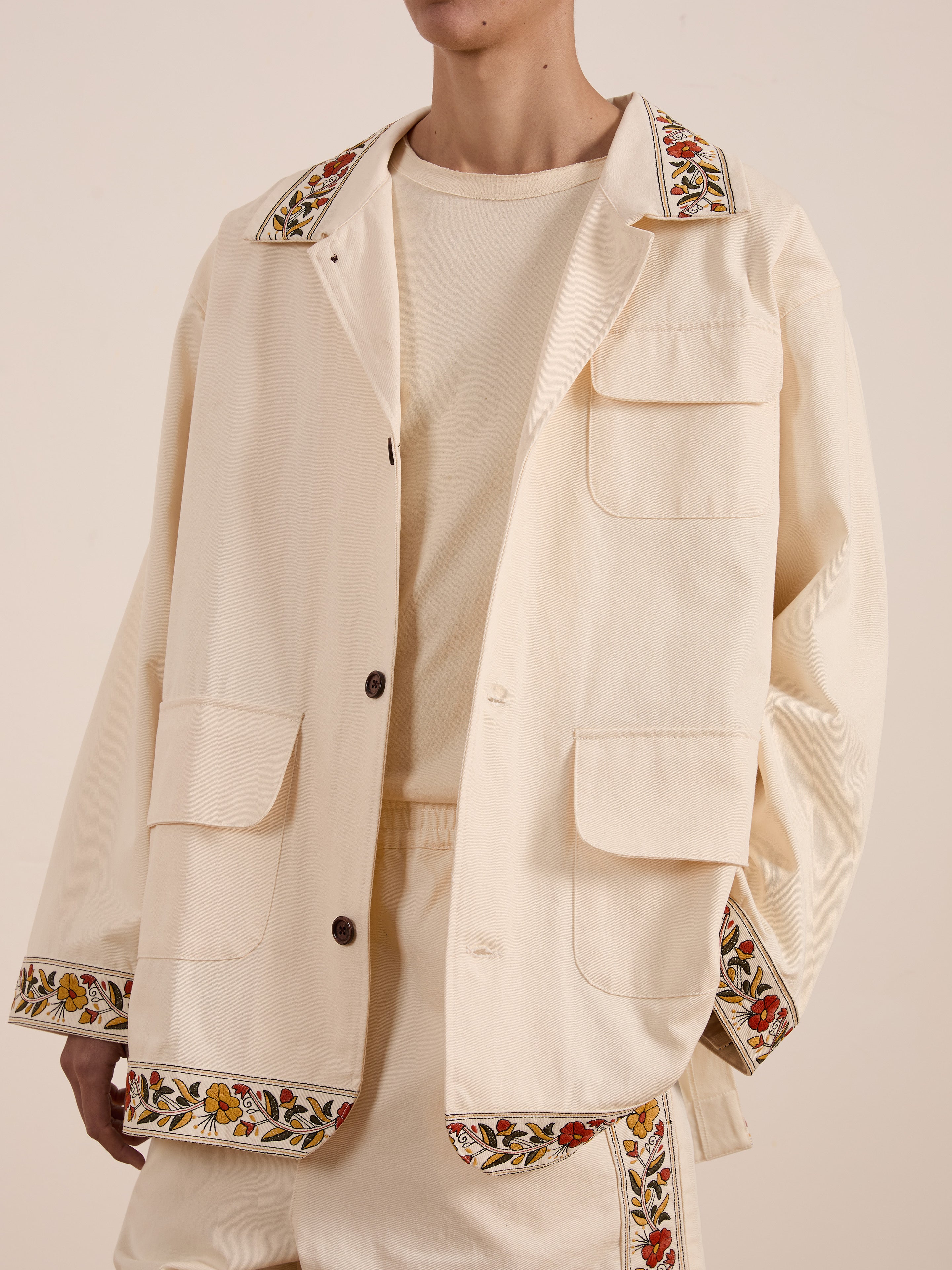 Adorned in FOUND's Kantha Floral Work Jacket, the person exudes vintage charm, blending classic elegance with modern flair through its cream-colored design and intricate floral details on the collar and sleeves.