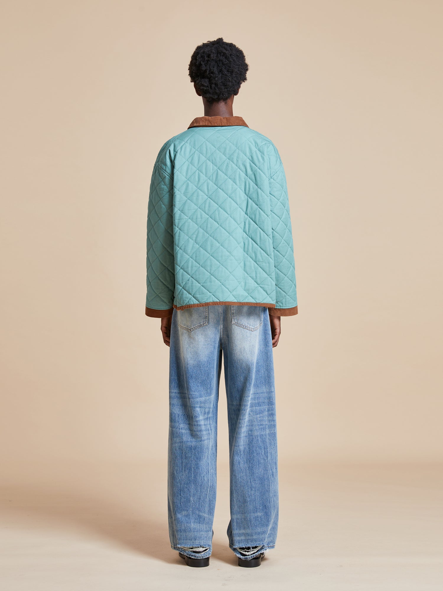 The back view of a woman wearing a Found Kashmir Meadow Quilt Jacket and jeans.