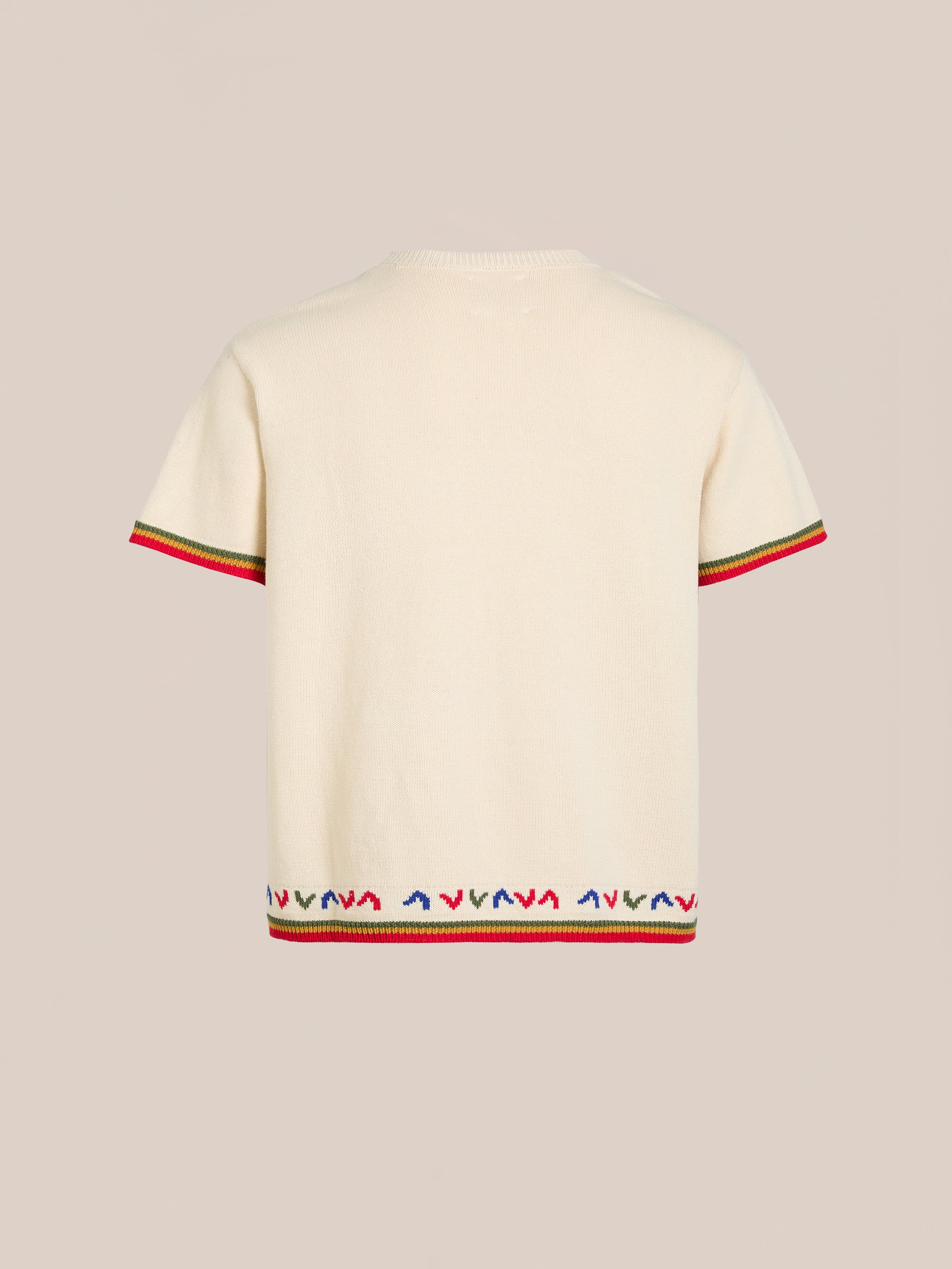 The Knit Flower Petal Tee by FOUND is a cream-colored short-sleeve sweater with vintage charm, featuring red, green, and blue patterned trim on the sleeves and hem. Its knit design shines against a neutral background.