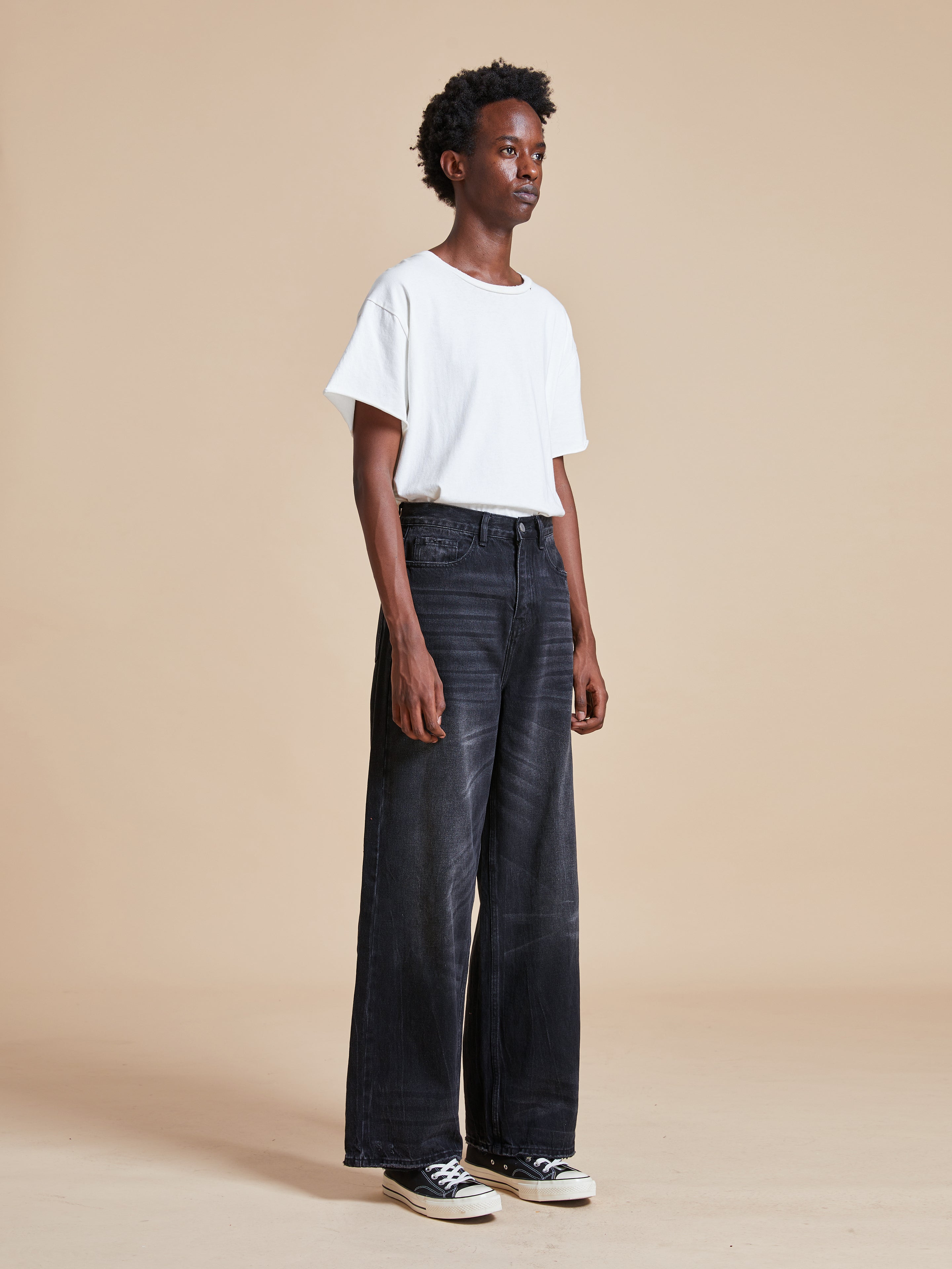 A man wearing a white t-shirt and Lacy Baggy Jeans with distressed hems by Found.