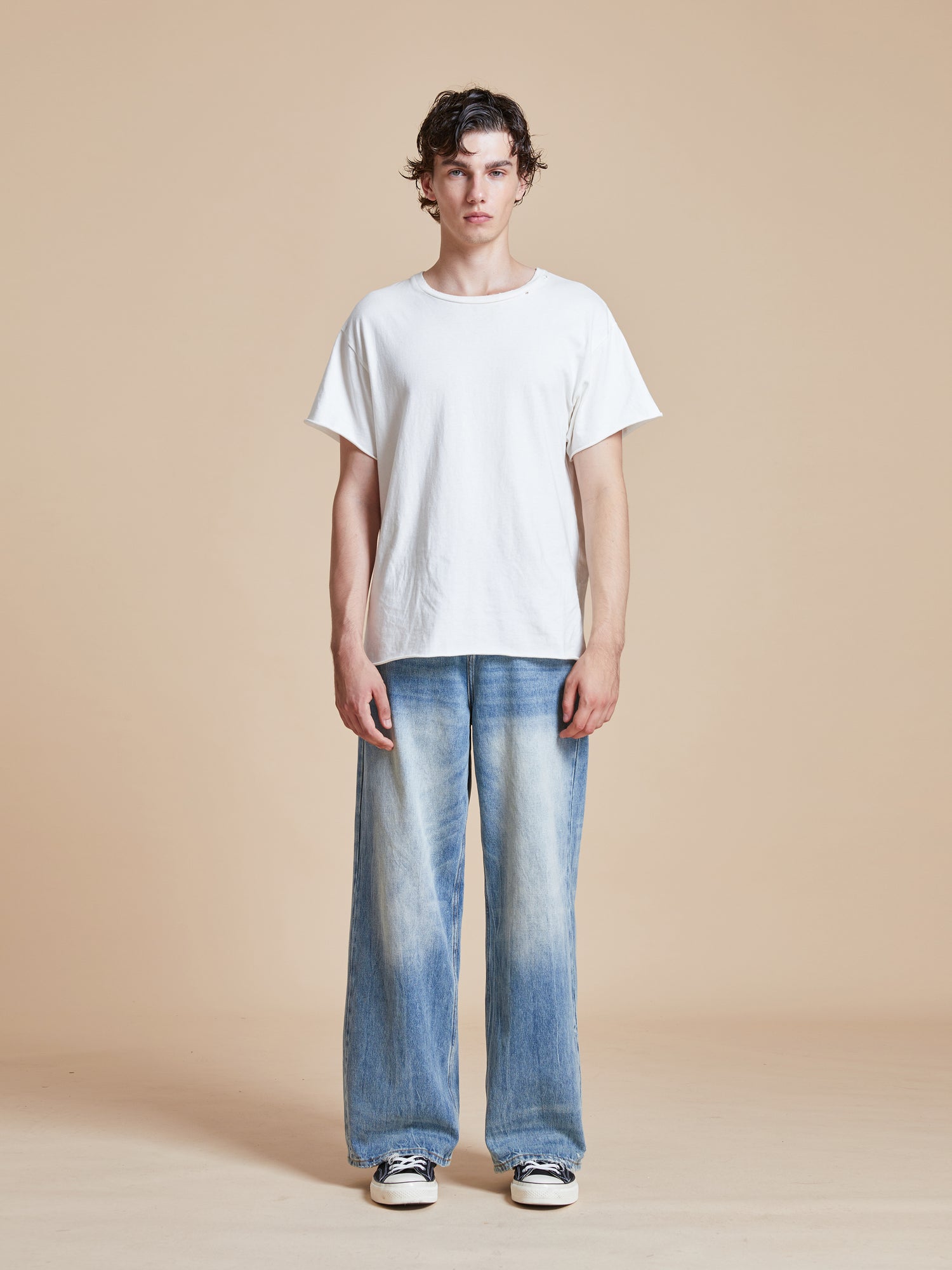 A man wearing a white t-shirt and Found's Lacy Baggy Jeans Blue.