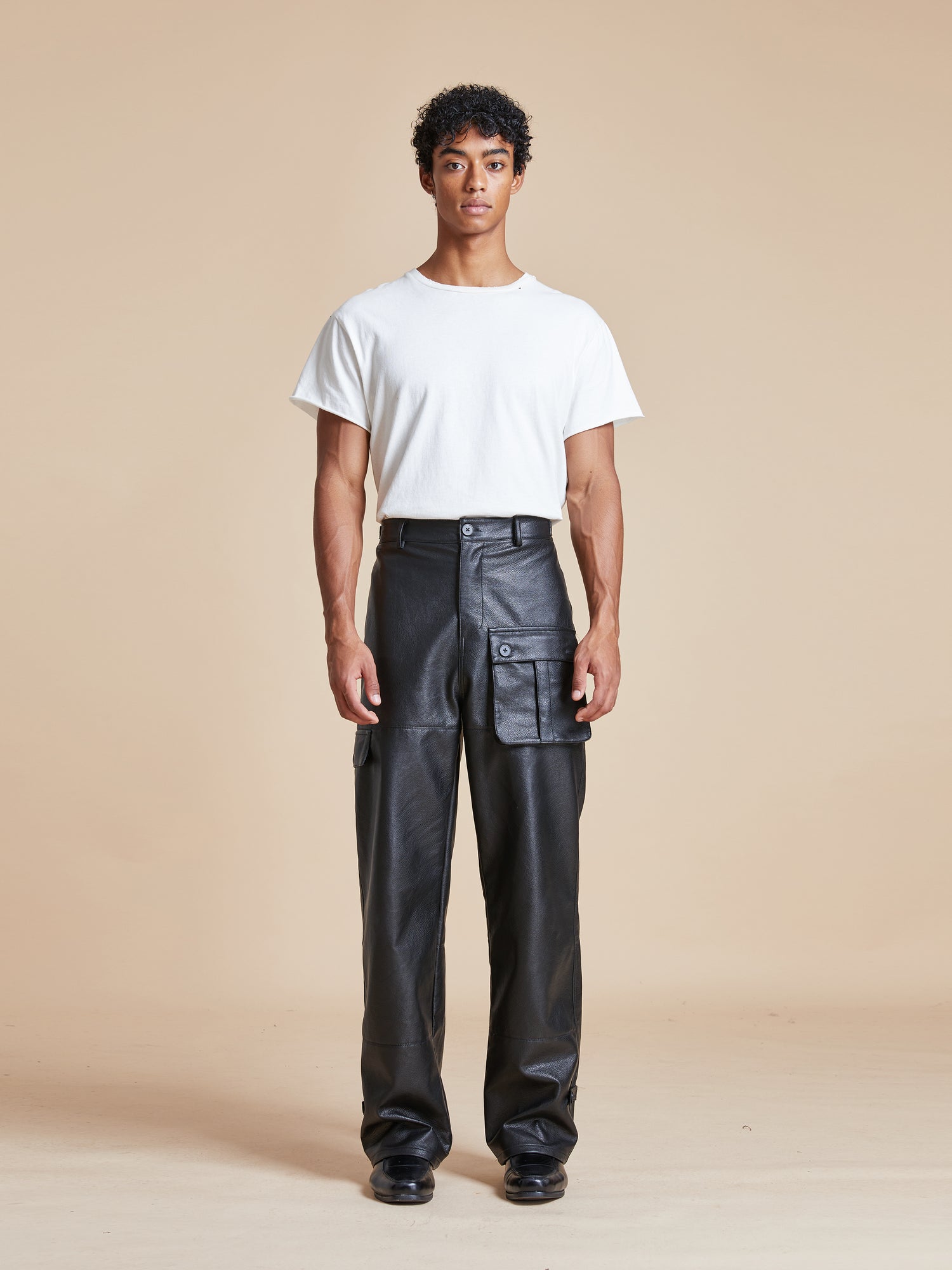 A man wearing Found faux leather cargo pants and a white t-shirt.
